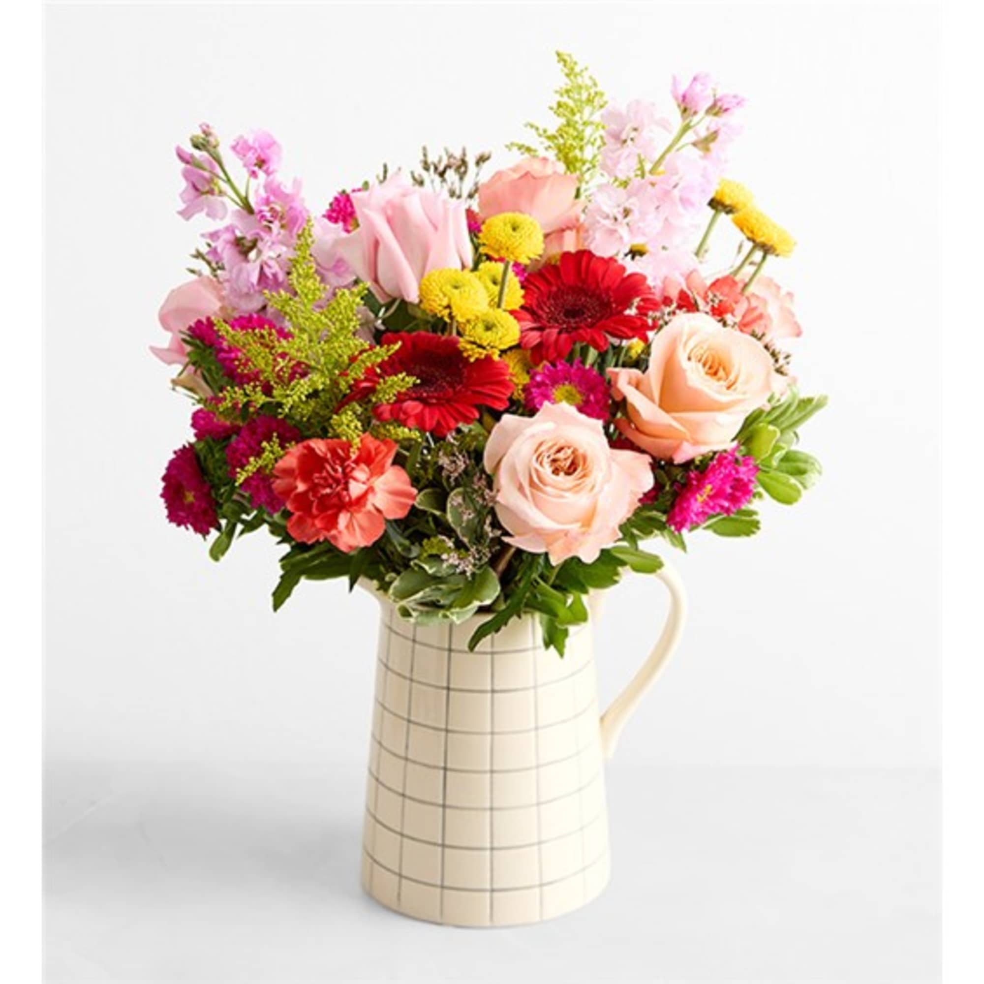 Mixed bouquet of pink, red, and yellow flowers in a cream checkered pitcher