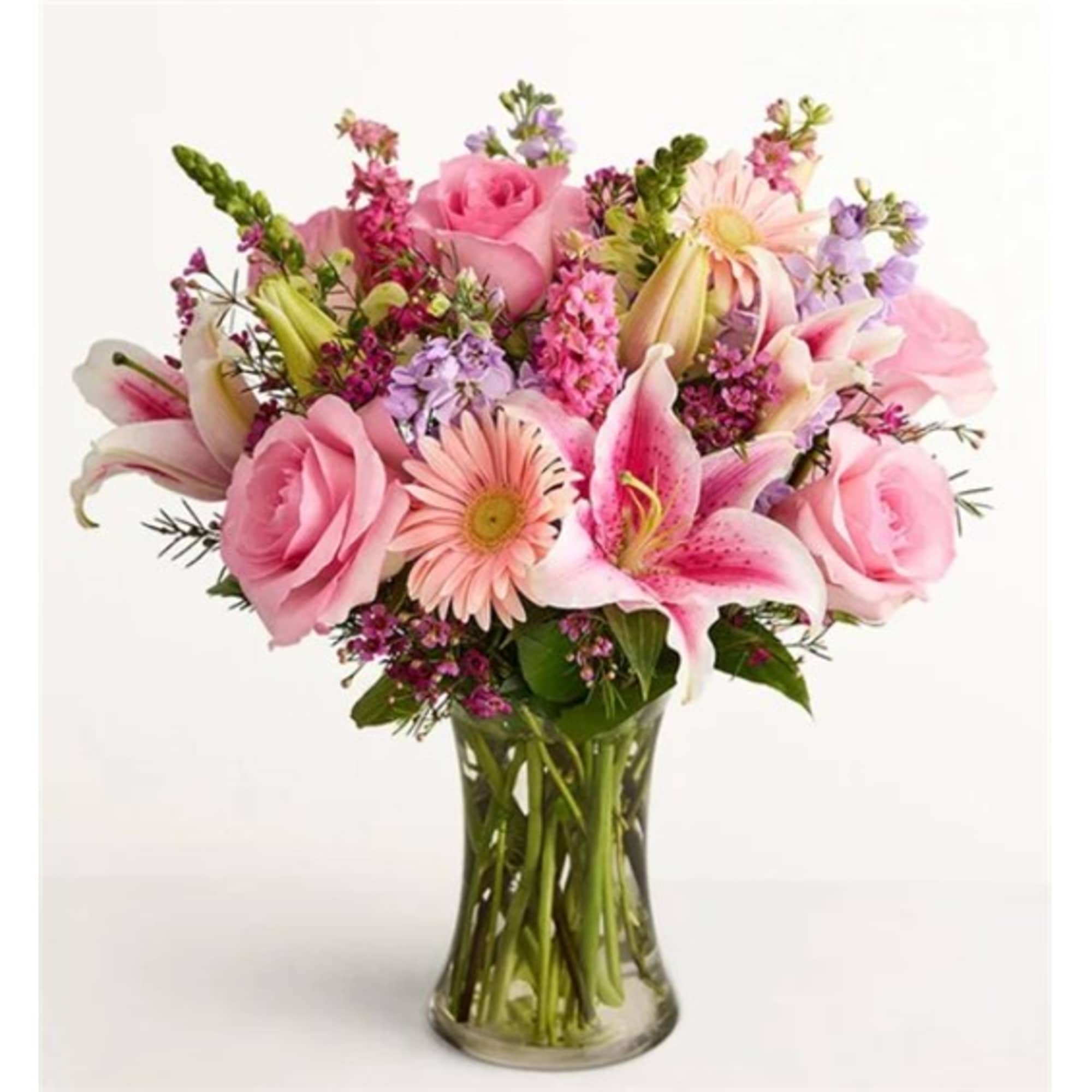 Pink roses and lilies arranged in a clear glass vase