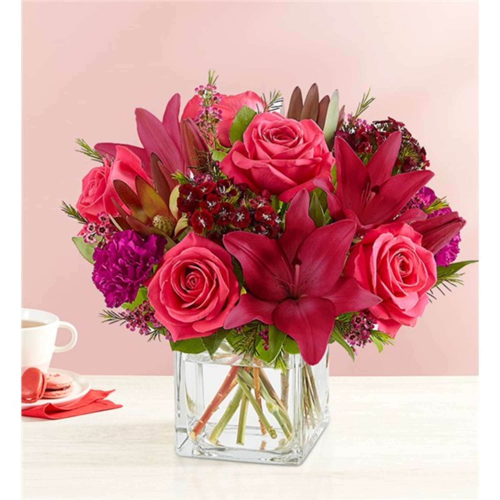 Pink roses and red lilies arranged in a clear glass vase