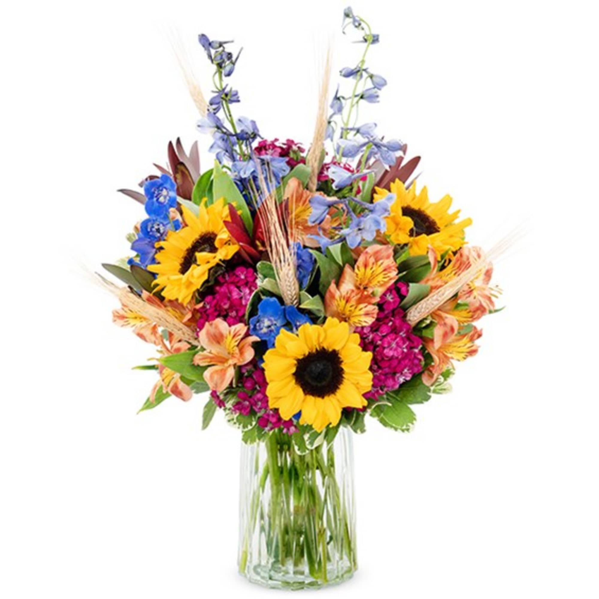Bright mixed bouquet with sunflowers and blue flowers in a clear glass vase