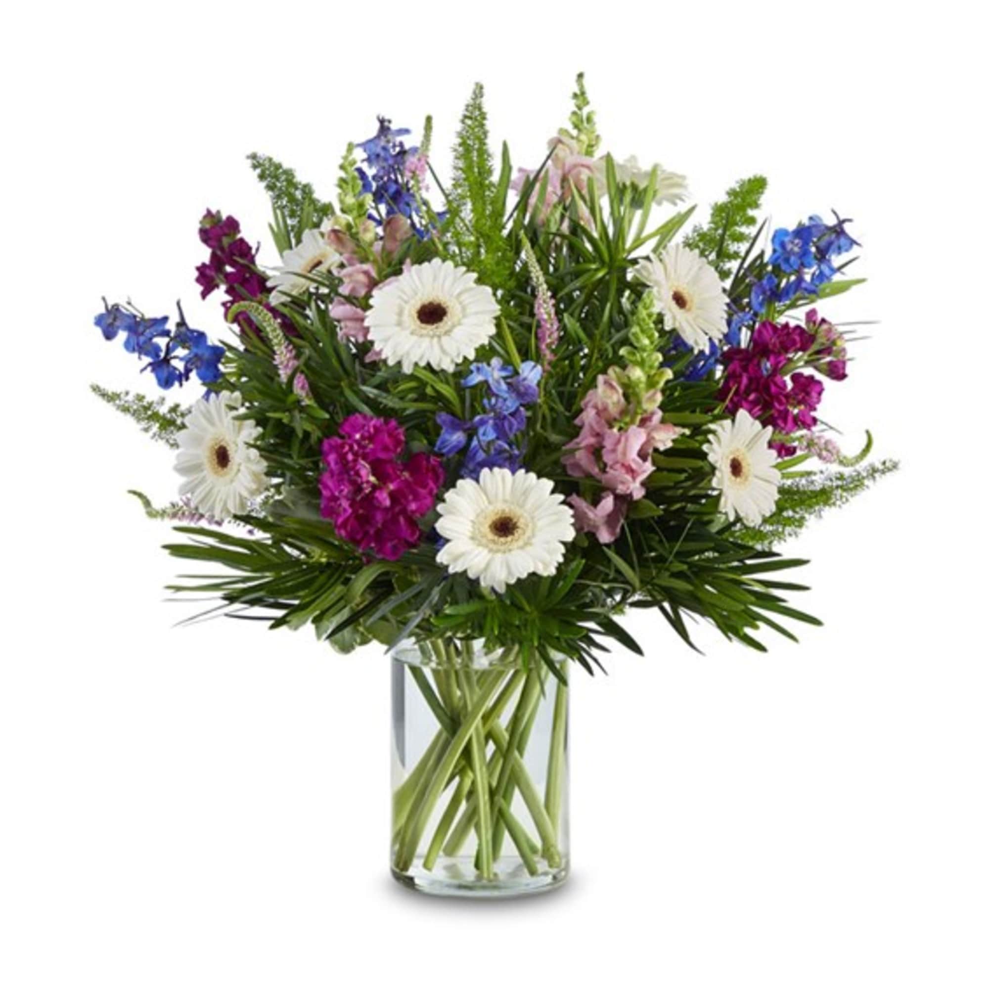Mixed bouquet of white daisies, pink and blue flowers in a clear glass vase
