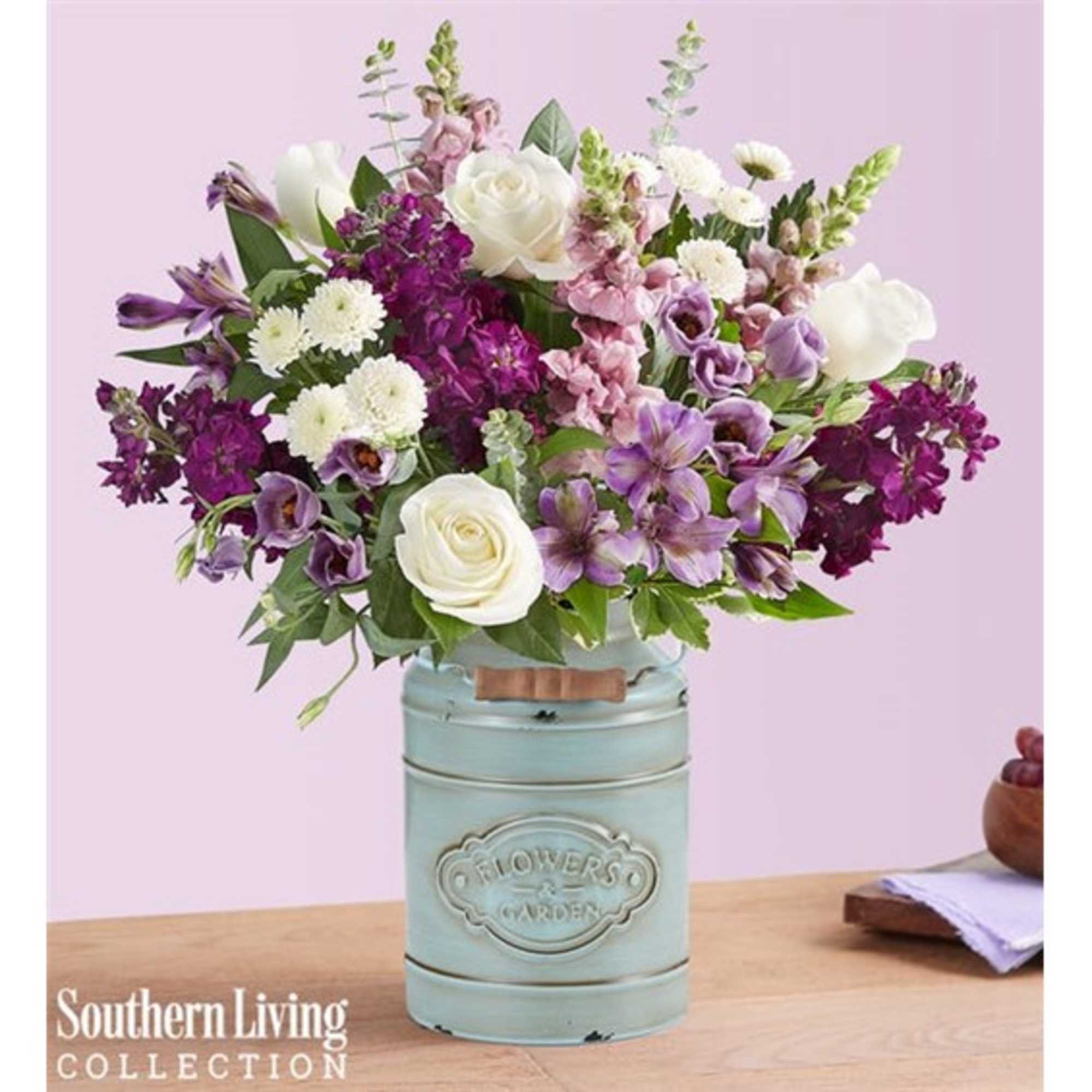 Mixed purple and white flowers arranged in a pale blue metal container
