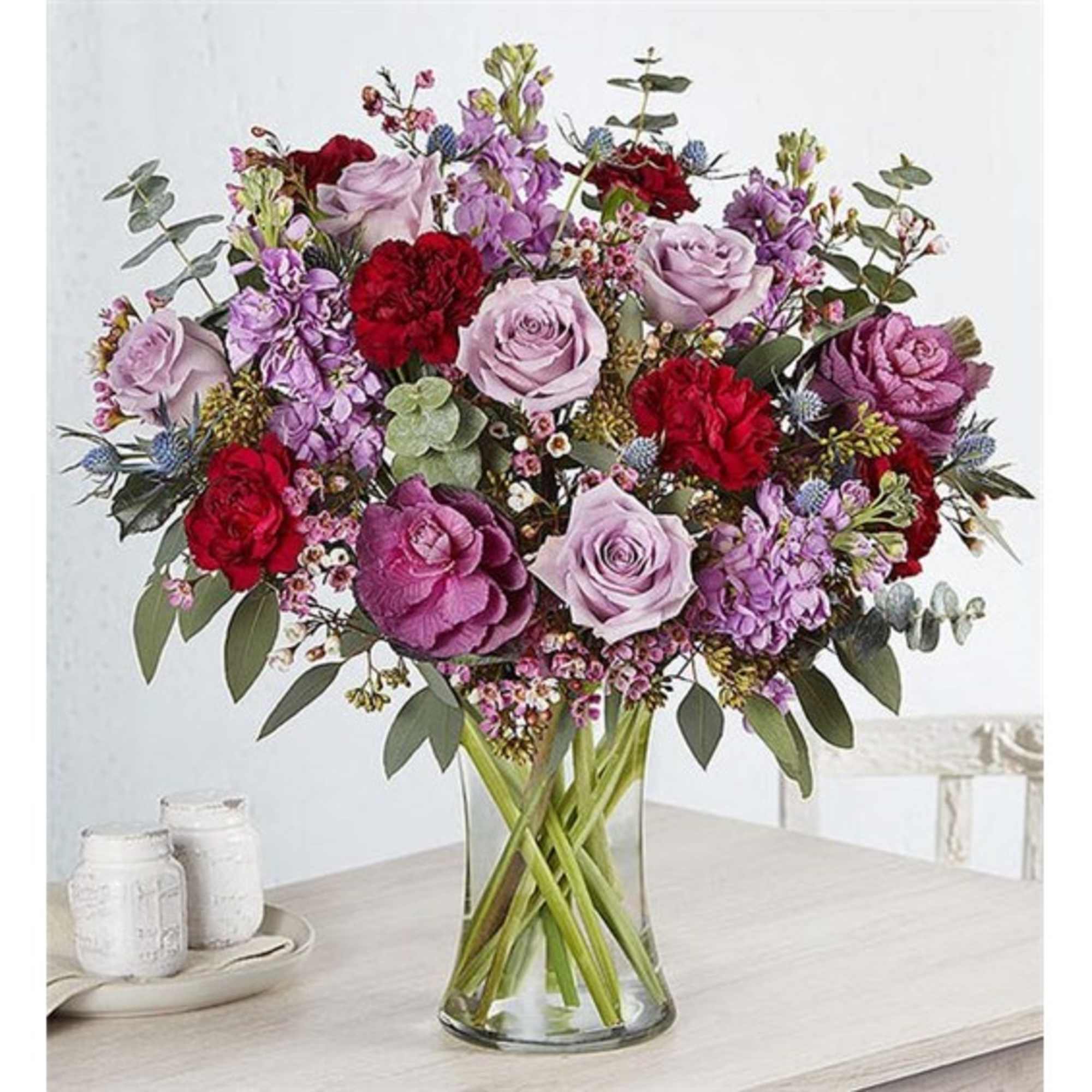 Mixed bouquet of pink, purple, and red flowers in a clear glass vase