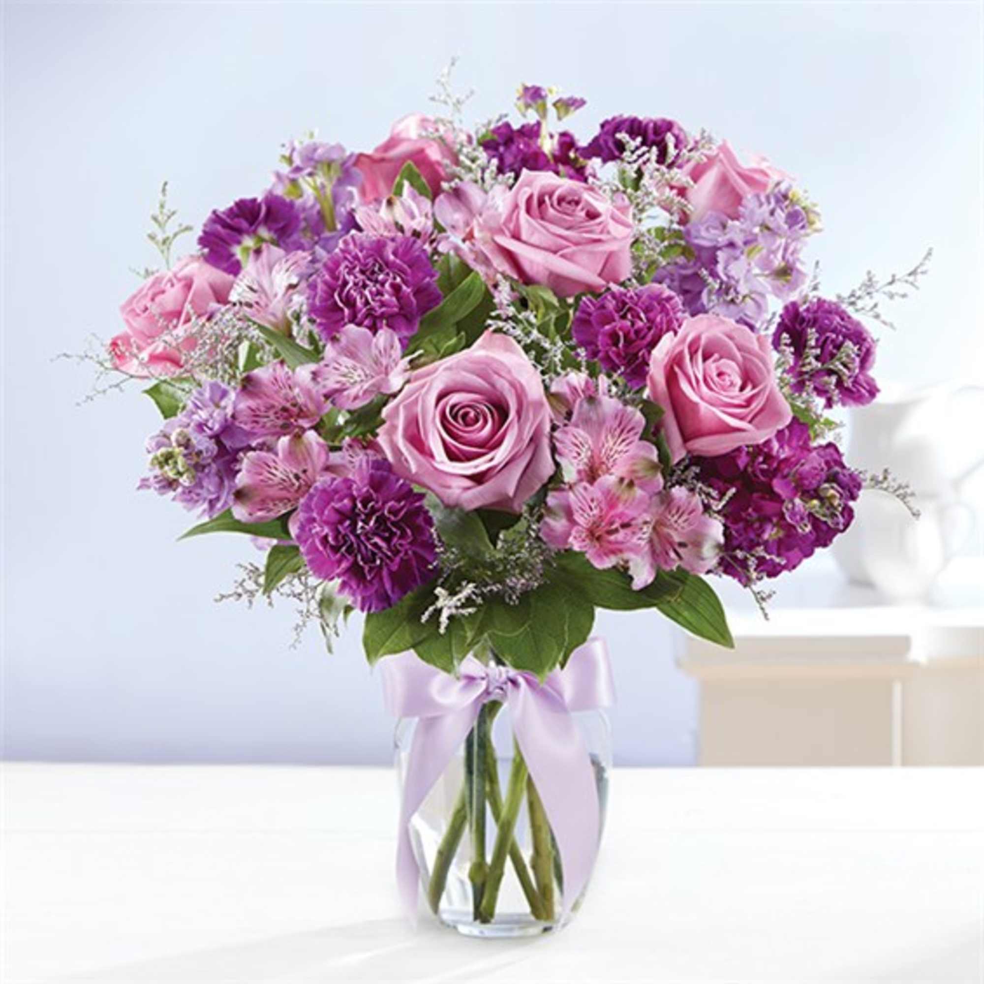 Pink and purple bouquet of roses and mixed flowers in a glass vase