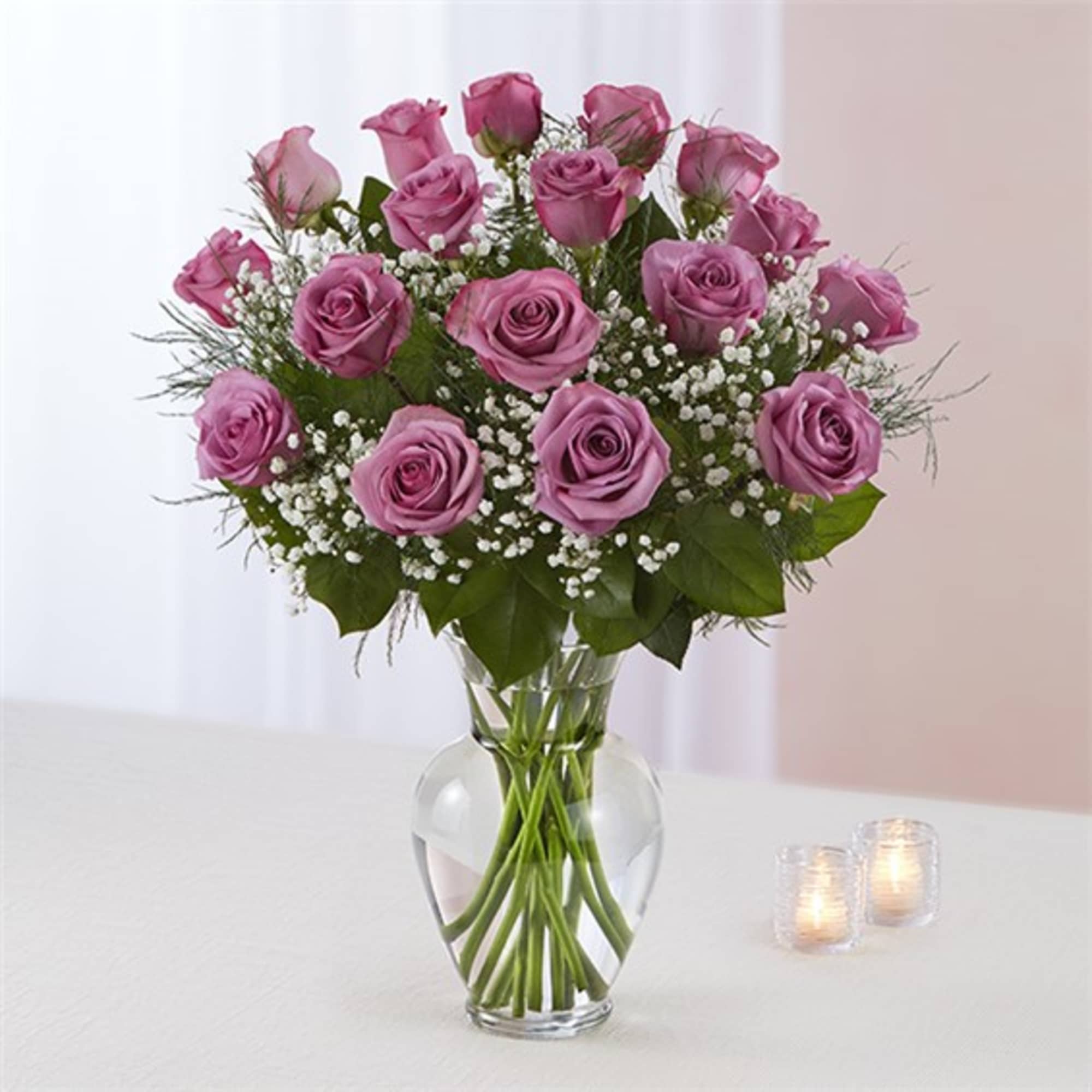 Pink roses arranged in a clear glass vase with small white filler flowers