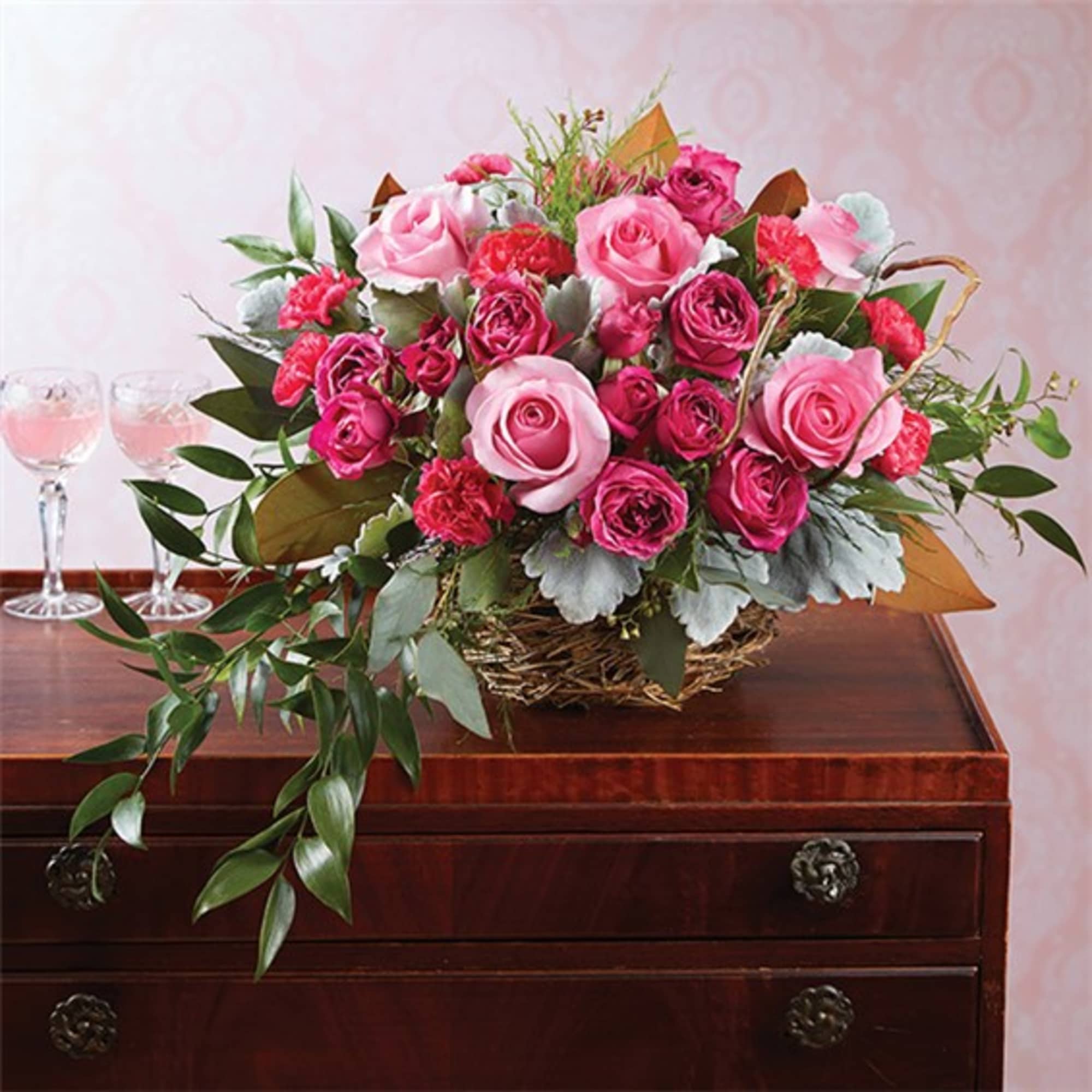 Pink rose bouquet in a woven basket on a wooden table