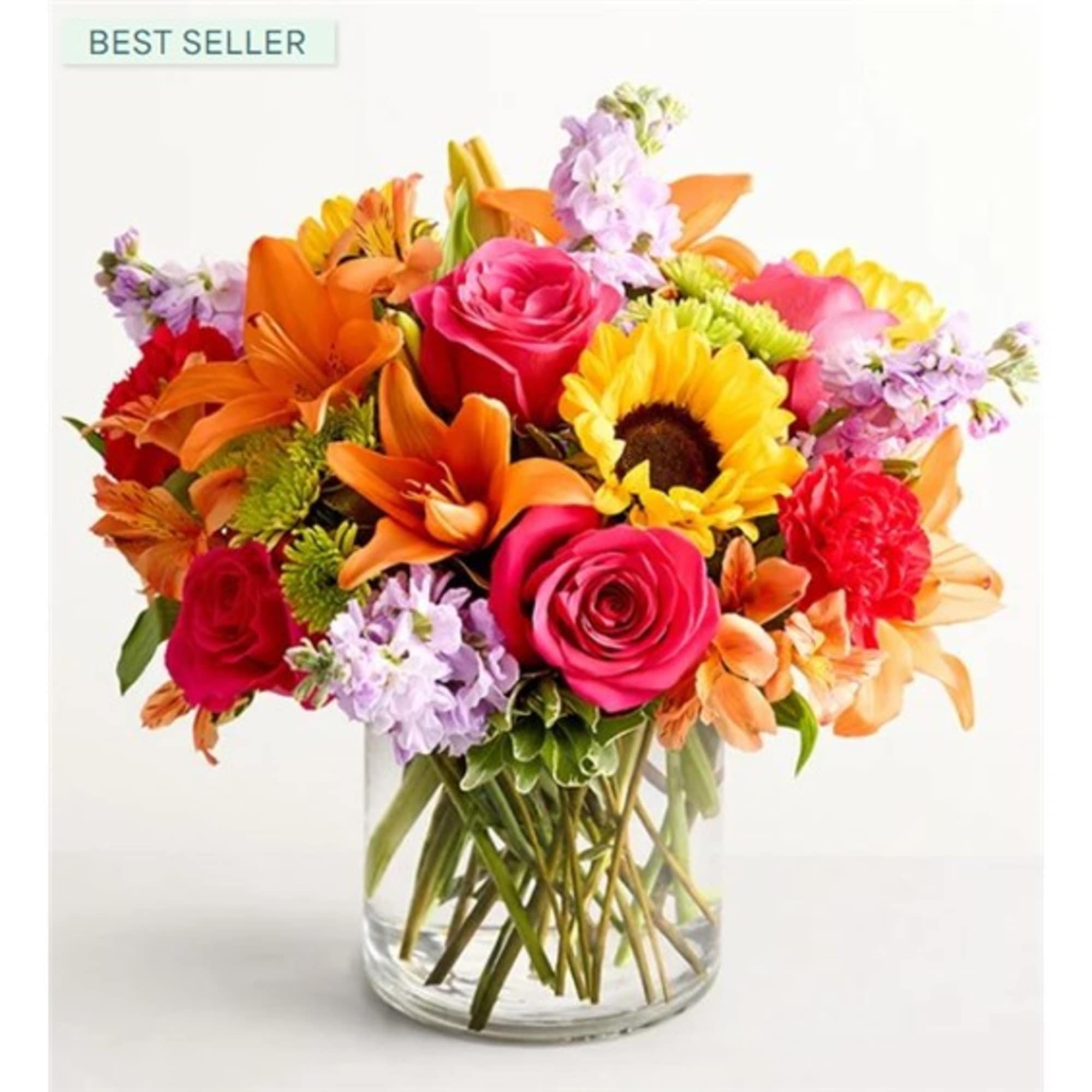 Bright mixed bouquet in a clear glass vase with roses, lilies, and sunflowers