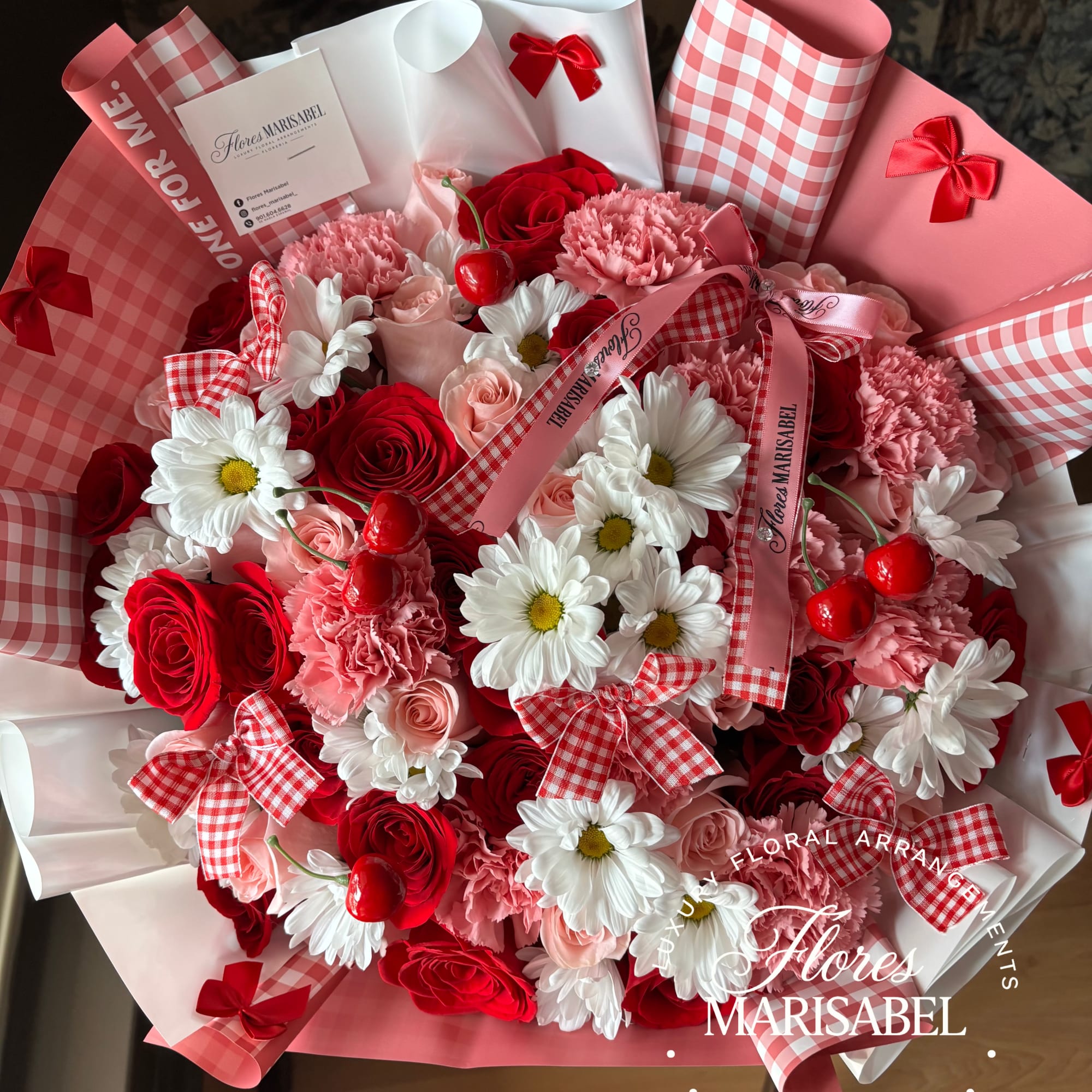 Bouquet of red roses, pink carnations, and white daisies with ribbon accents