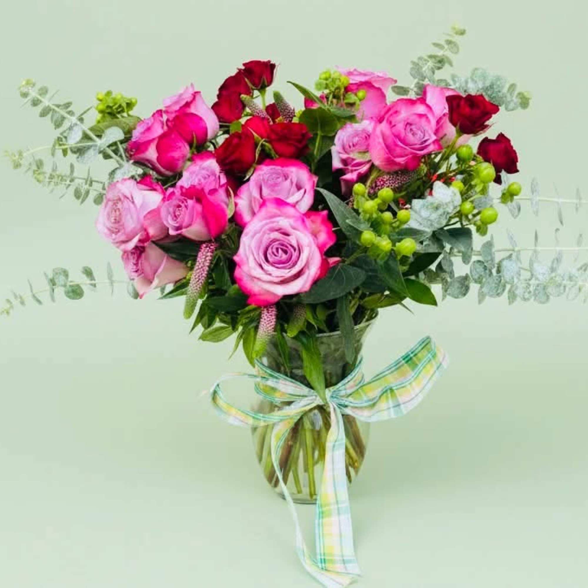Pink and red rose bouquet in a glass vase with a ribbon