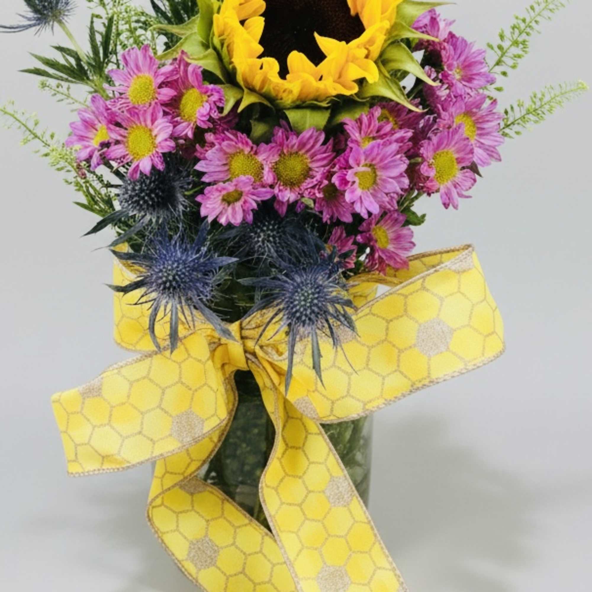 Sunflower bouquet with pink daisies and blue thistle, tied with a yellow ribbon