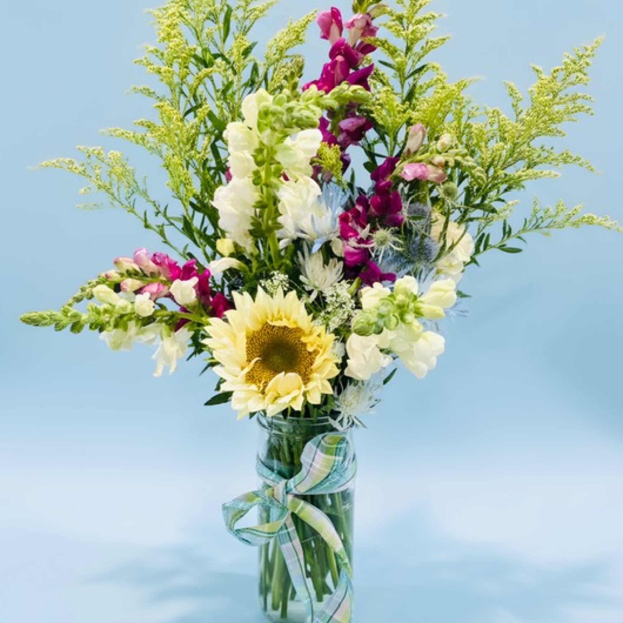 Mixed bouquet with a sunflower, snapdragons, and a glass vase
