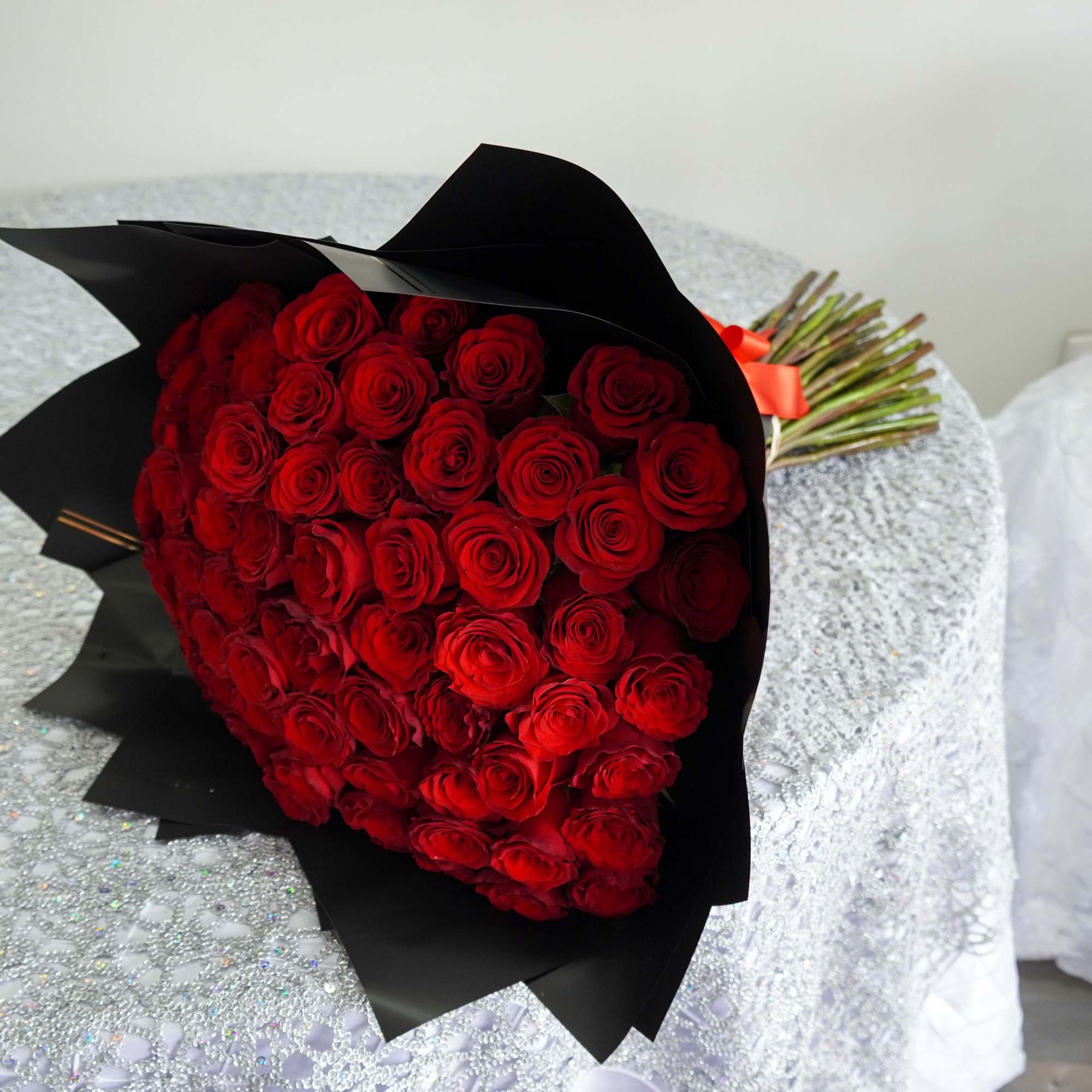 Bouquet of red roses wrapped in black paper with a red ribbon