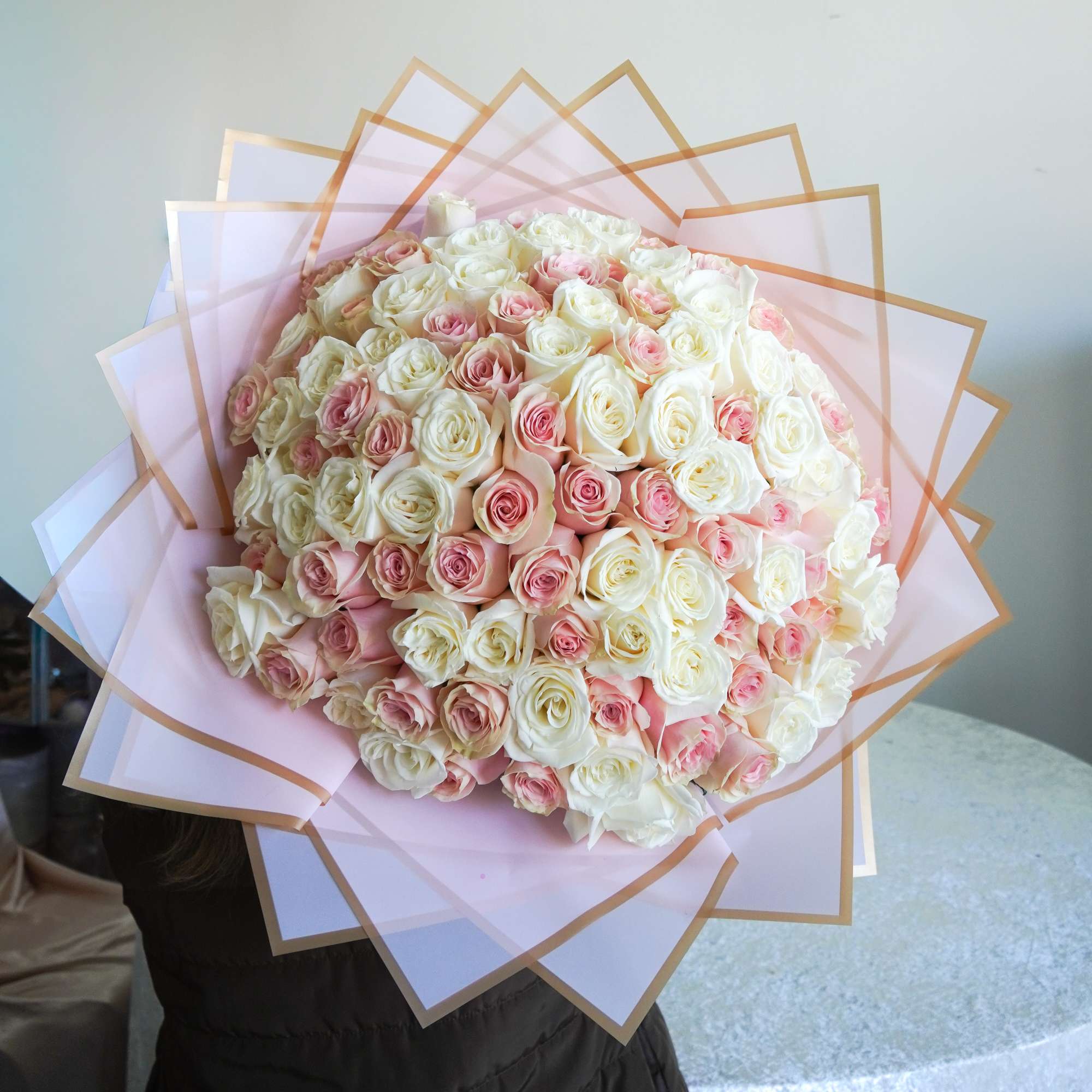 Large bouquet of white and pale pink roses wrapped in pink paper
