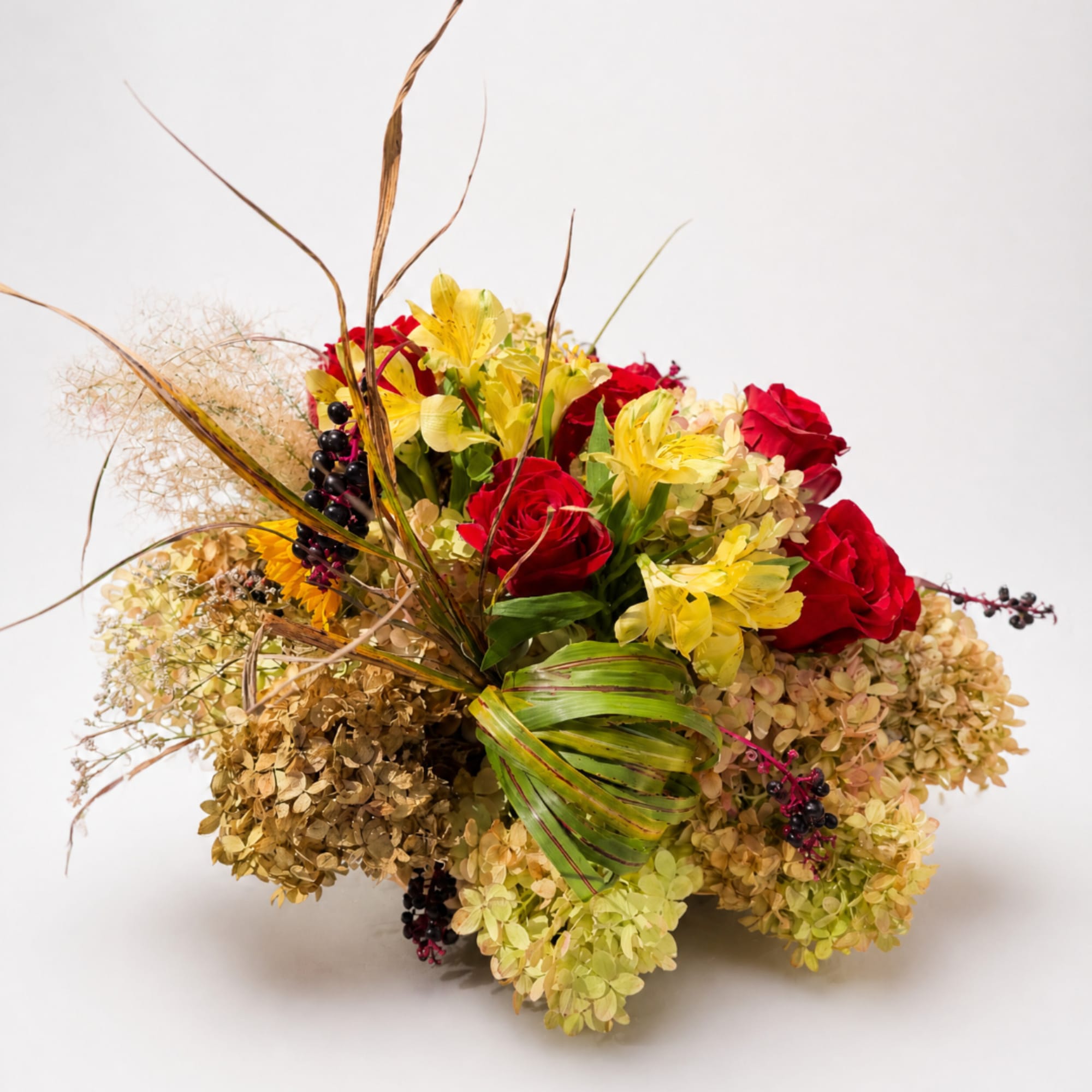 Bouquet of red roses and yellow lilies with dried hydrangea and decorative grasses