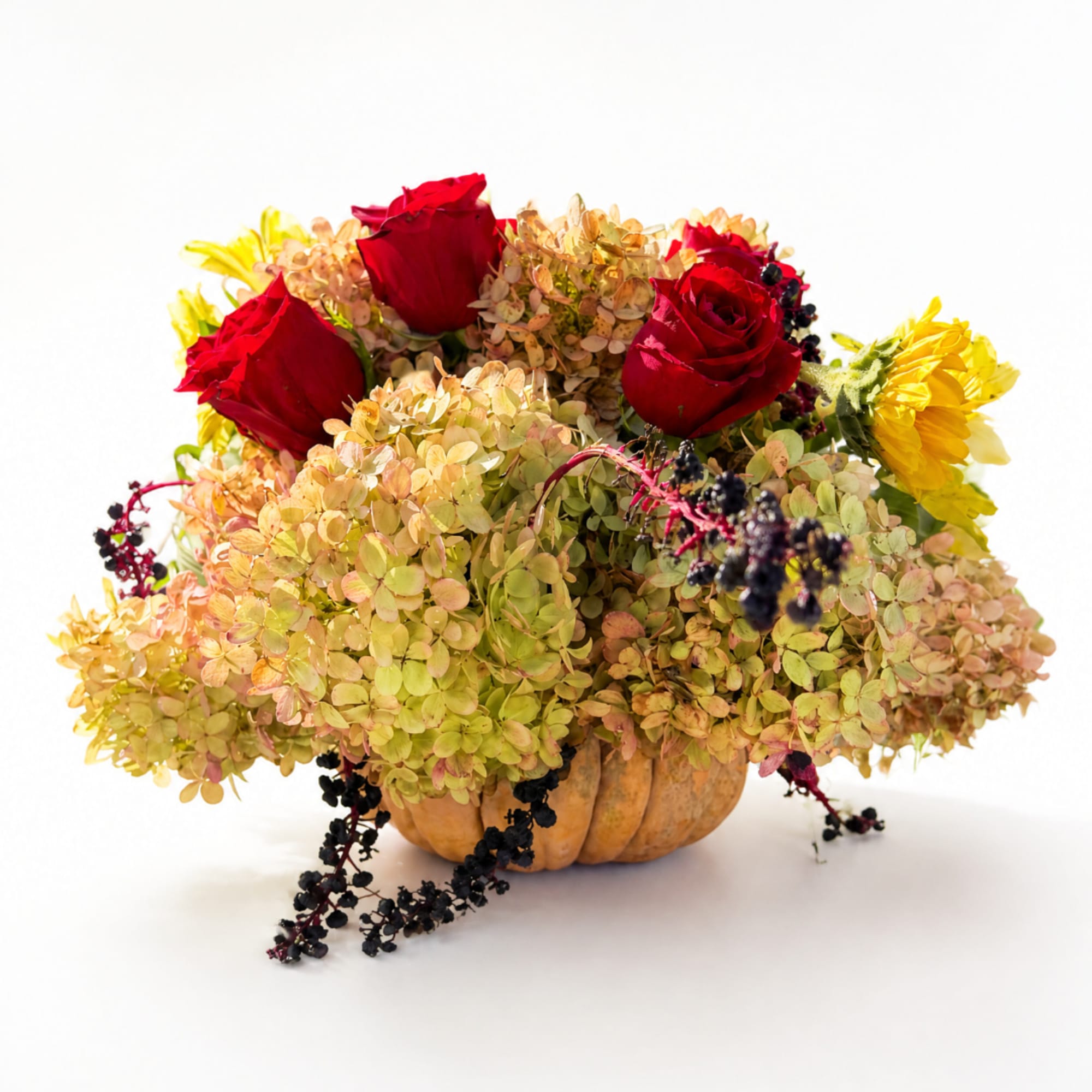 Red roses and yellow flowers arranged in a pumpkin vase