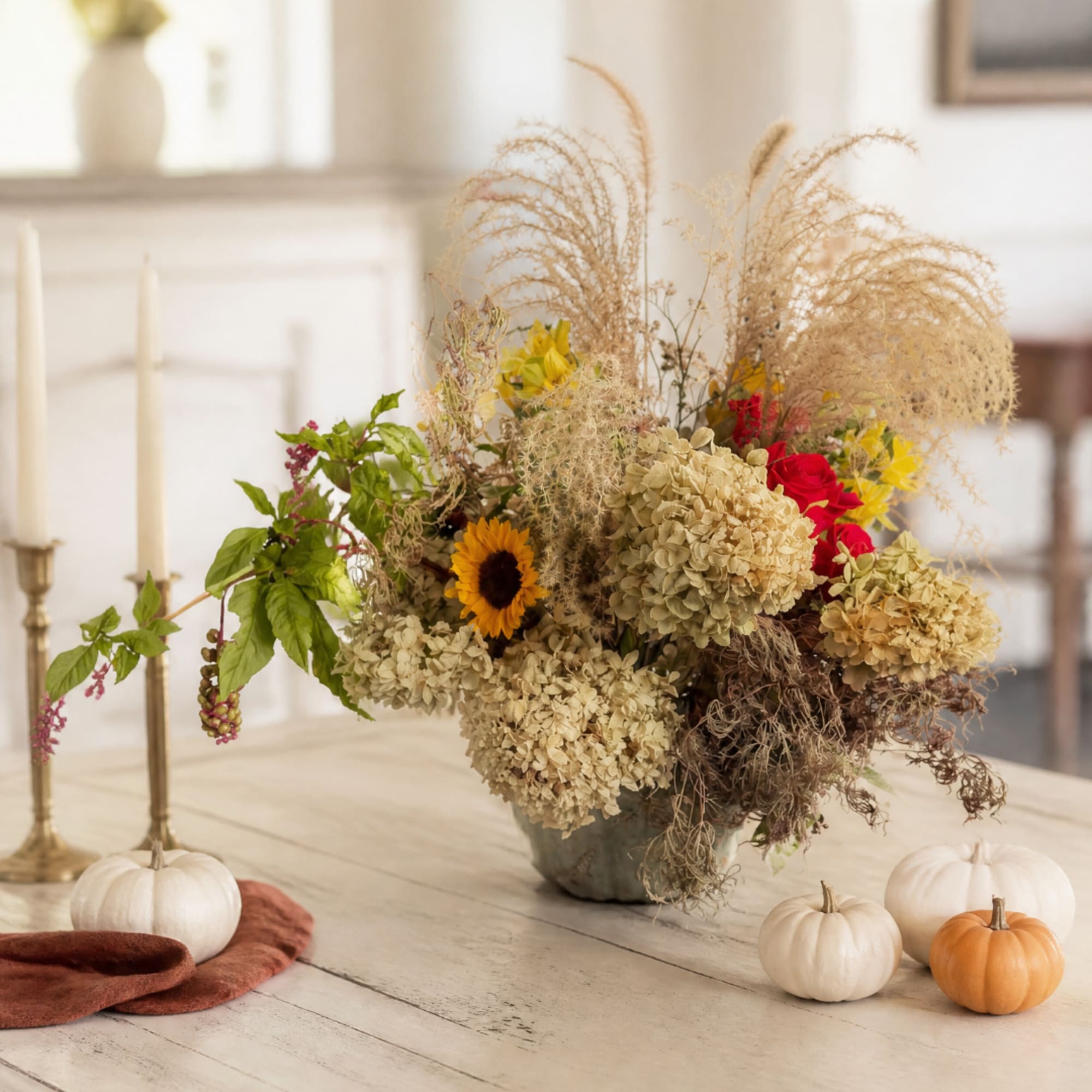 Autumn floral arrangement with sunflowers, roses, and dried grasses in a vase