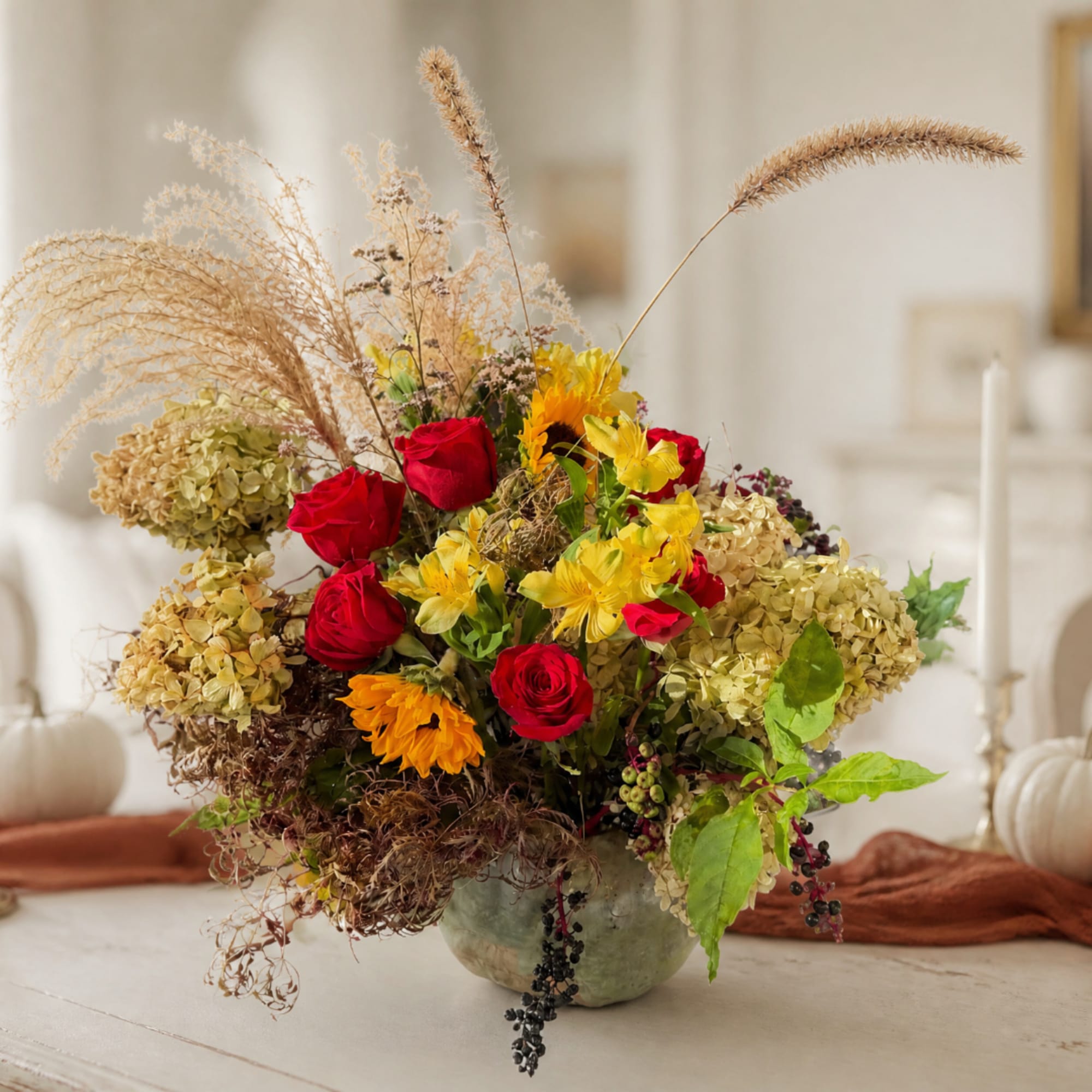 Mixed bouquet with red roses, yellow flowers, and dried grasses in a vase