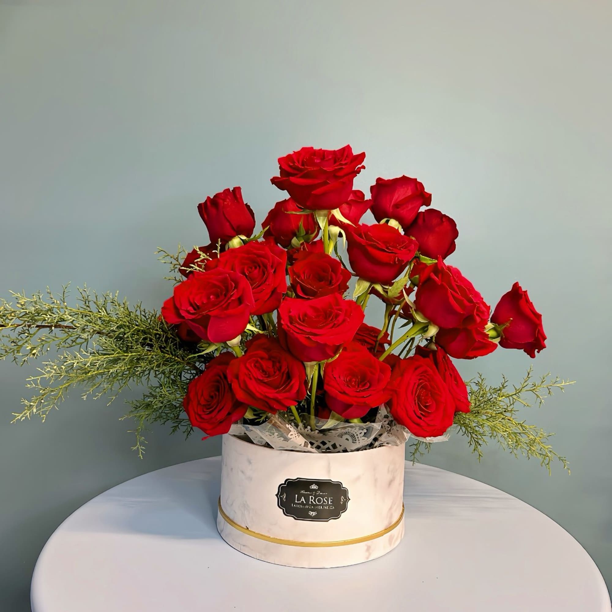 Red roses arranged in a white round box on a table