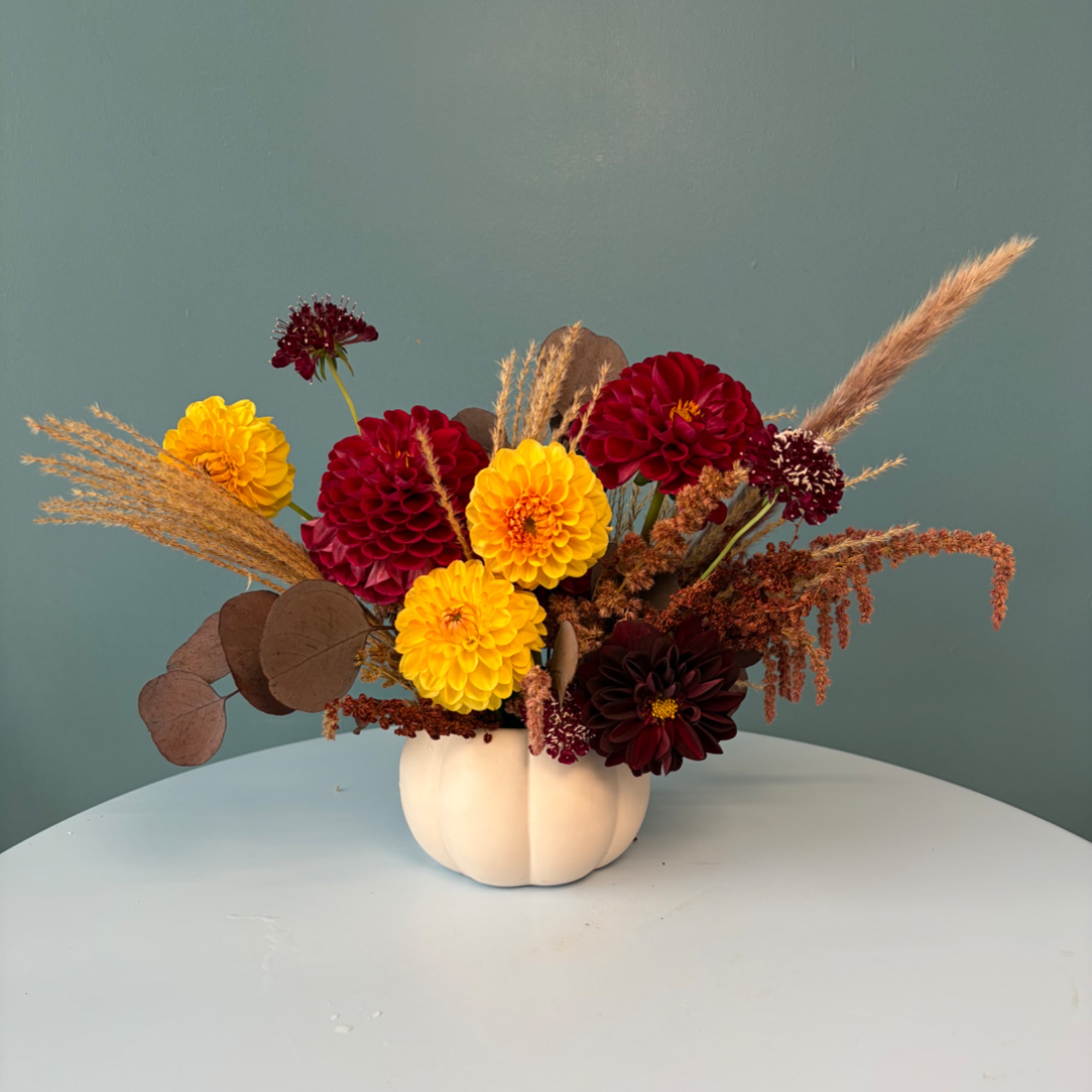 Dahlia arrangement in a white pumpkin vase with dried grasses