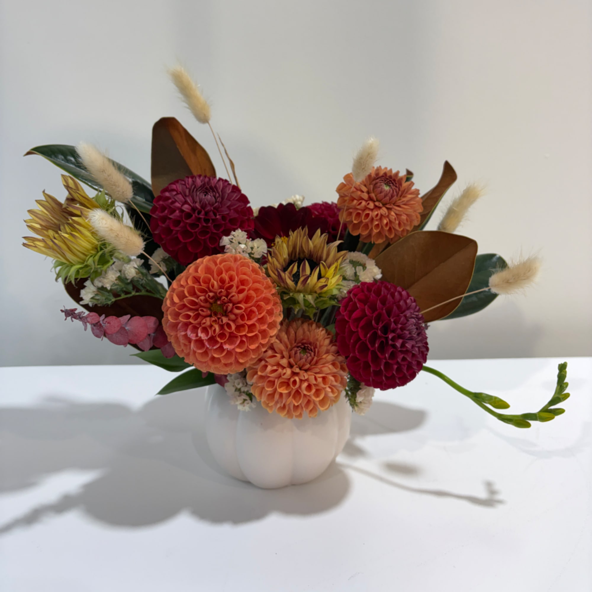 Colorful dahlia arrangement in a white vase