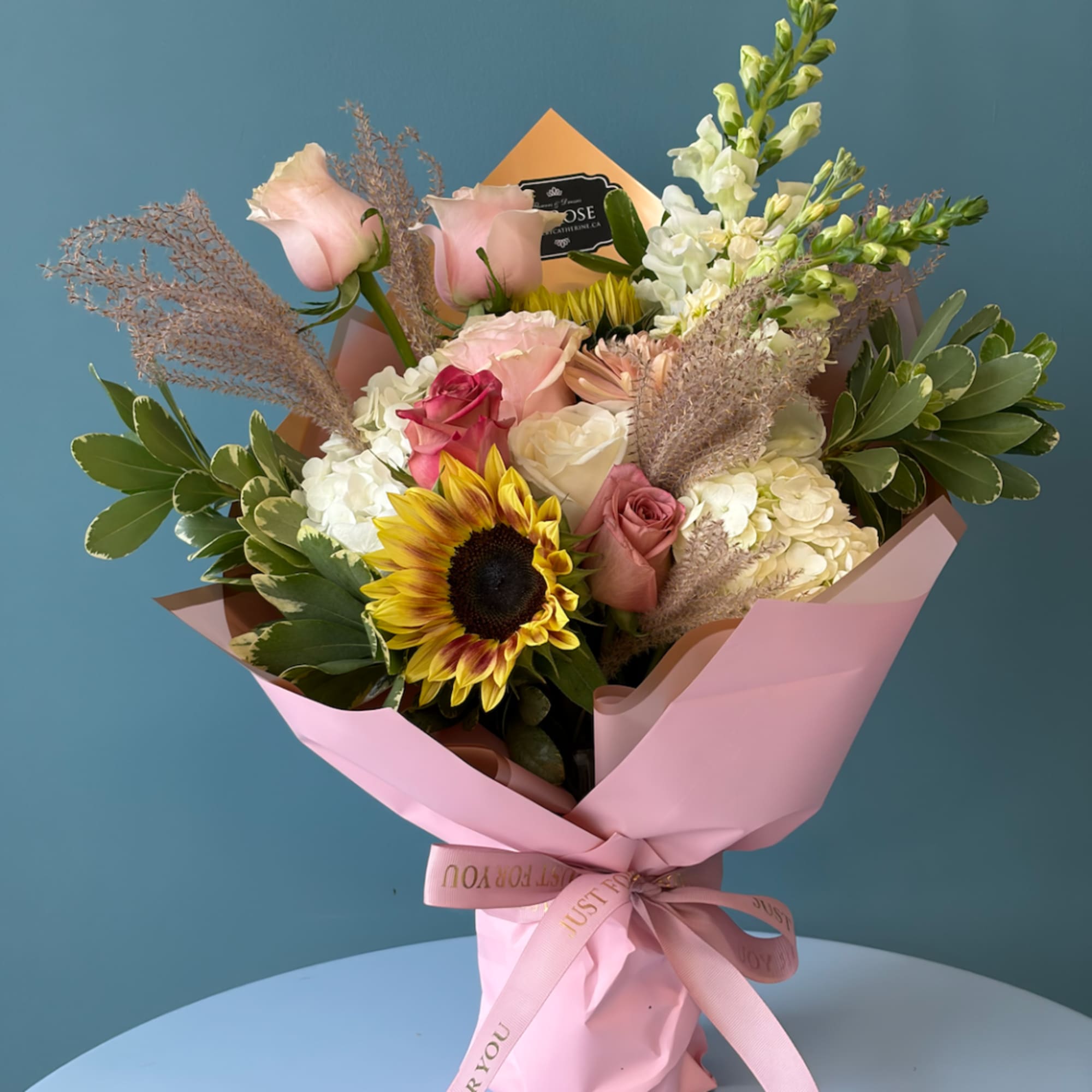 Pink and white mixed bouquet with a sunflower in pink wrapping