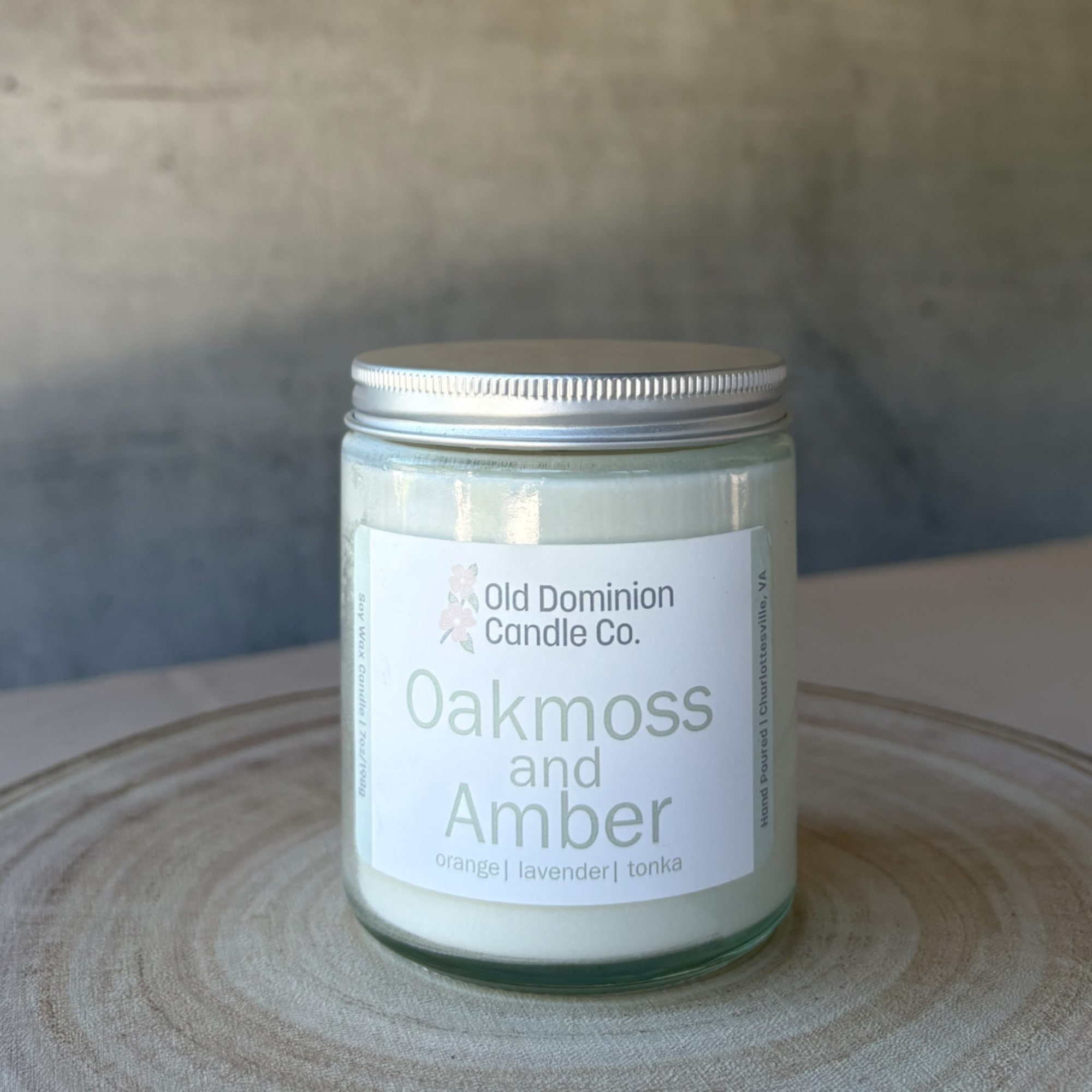 Jar candle labeled Oakmoss and Amber on a wooden surface