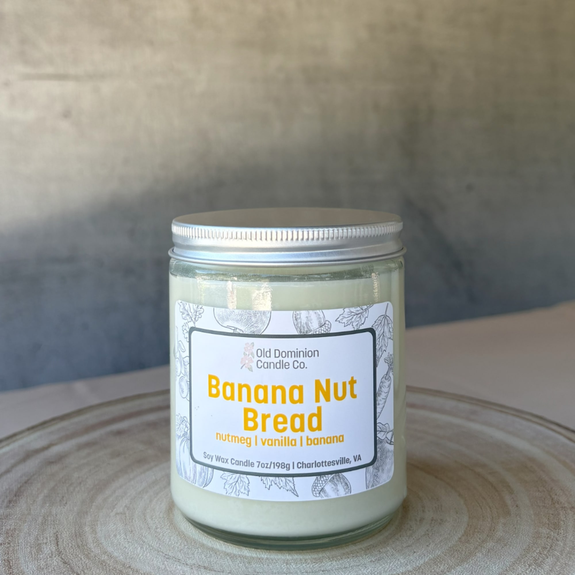 Jar candle labeled Banana Nut Bread on a wooden surface