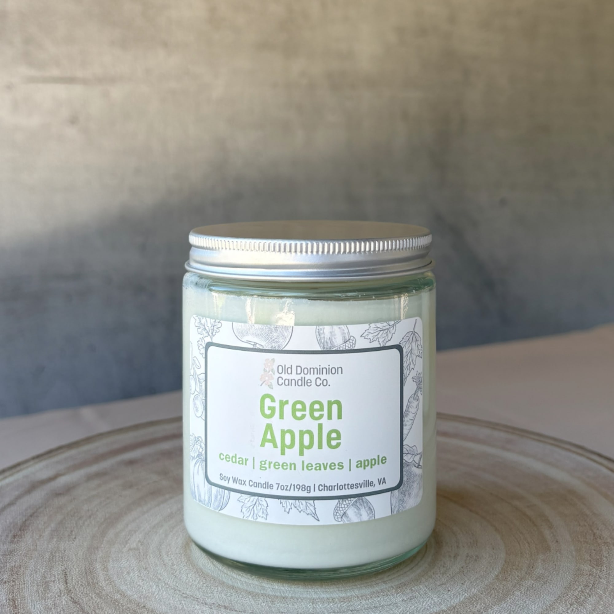Green apple scented candle in a glass jar with a silver lid