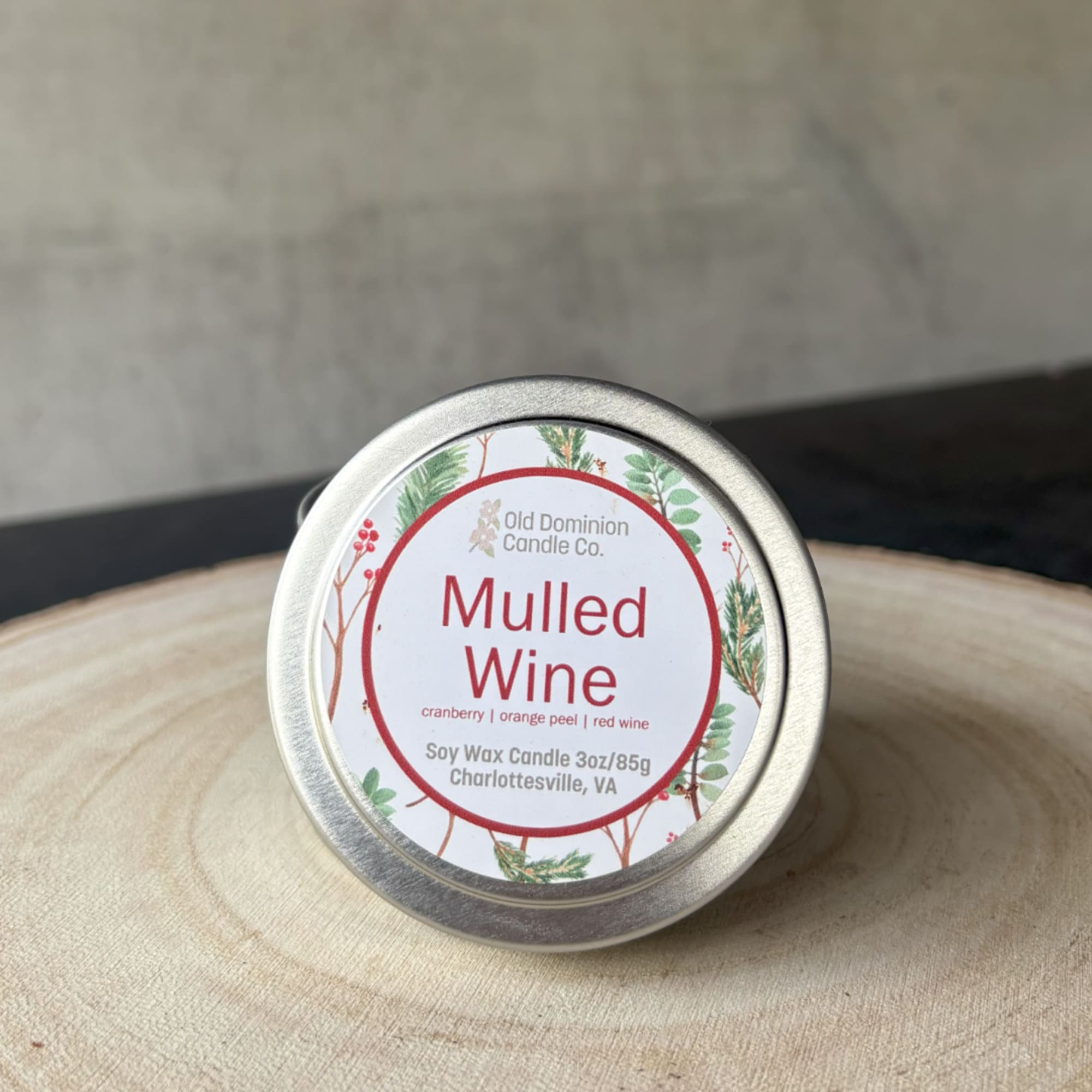 Tin candle labeled Mulled Wine on a wooden surface