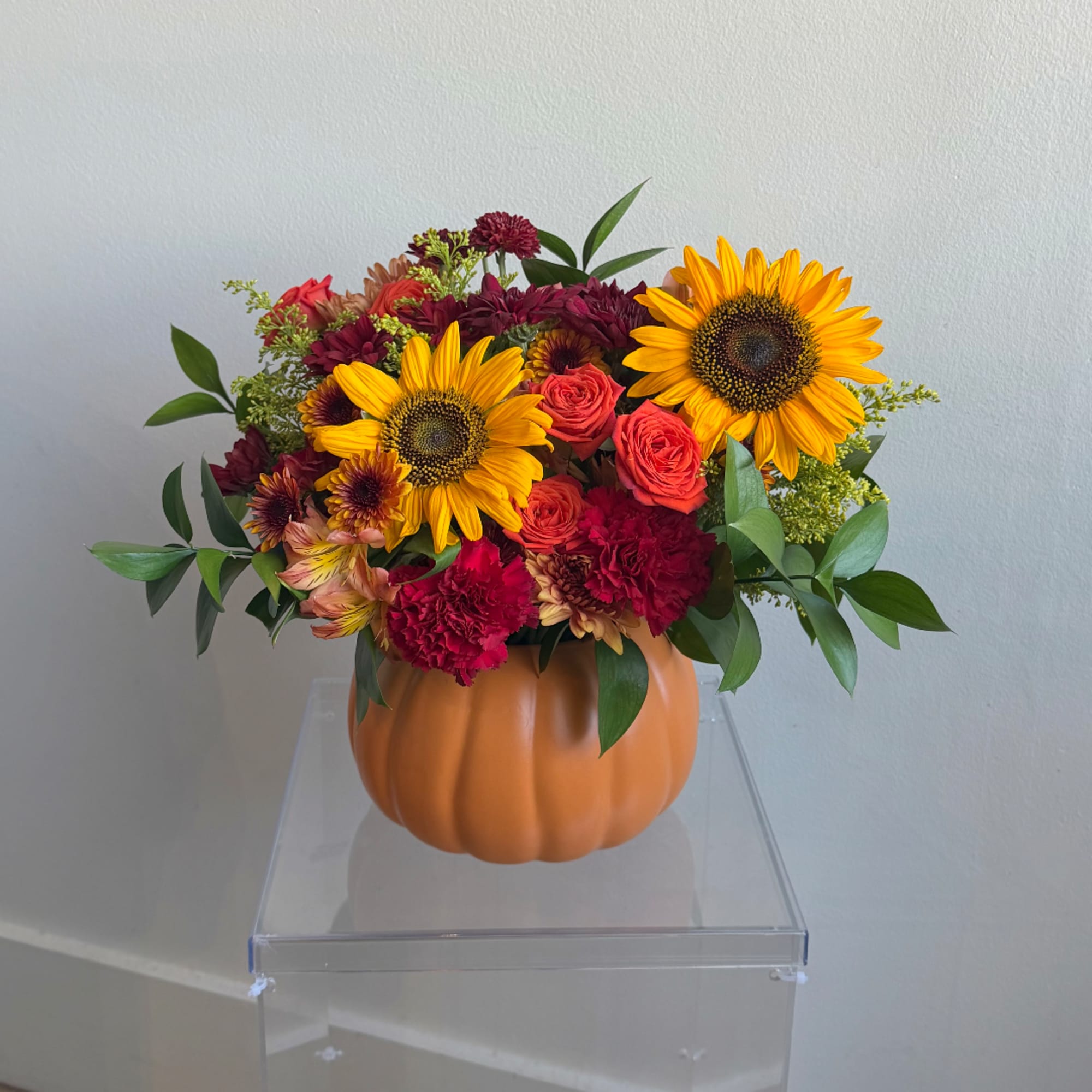 Mixed bouquet in a pumpkin-shaped vase with sunflowers and roses