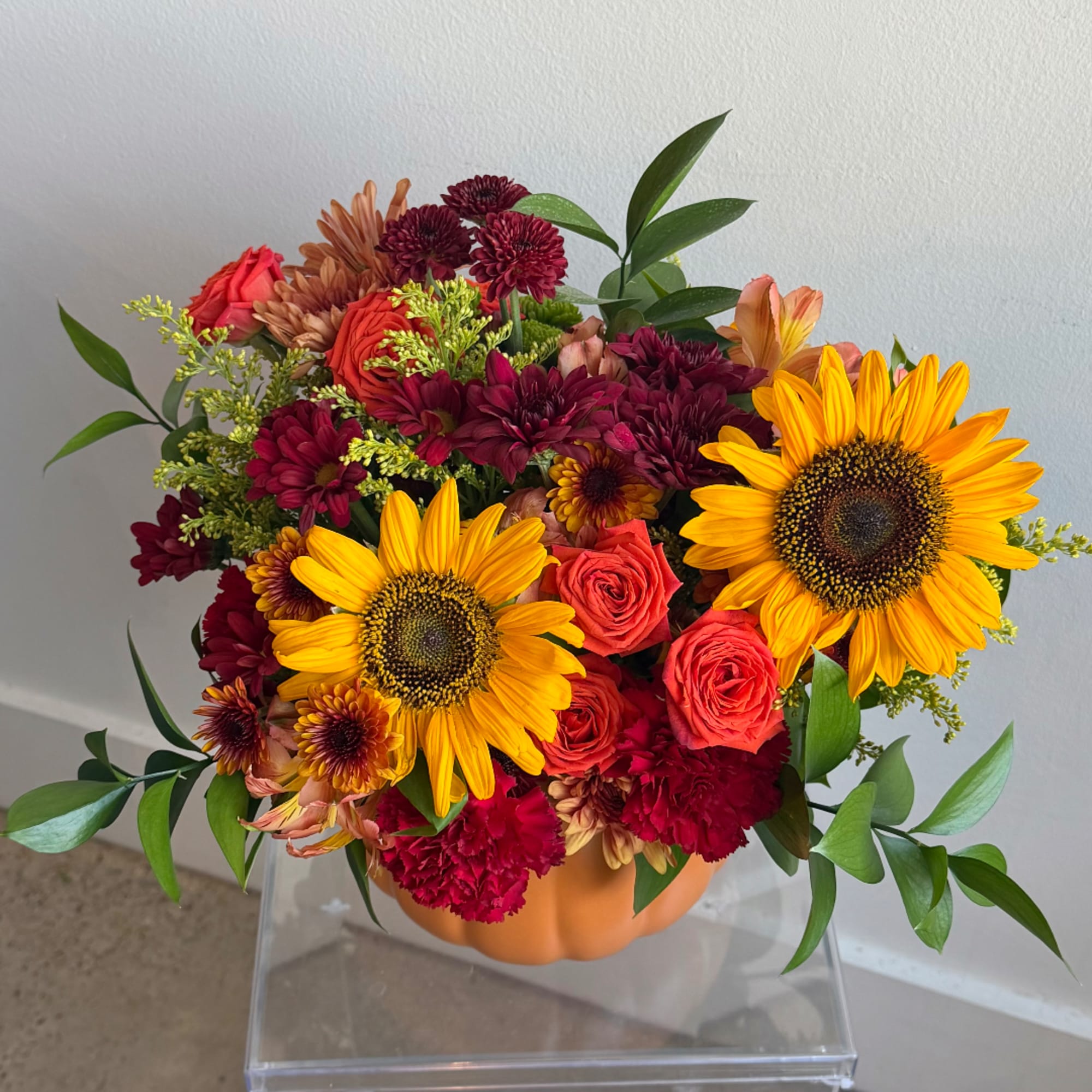 Bouquet of sunflowers, red roses, and burgundy mums in an orange vase
