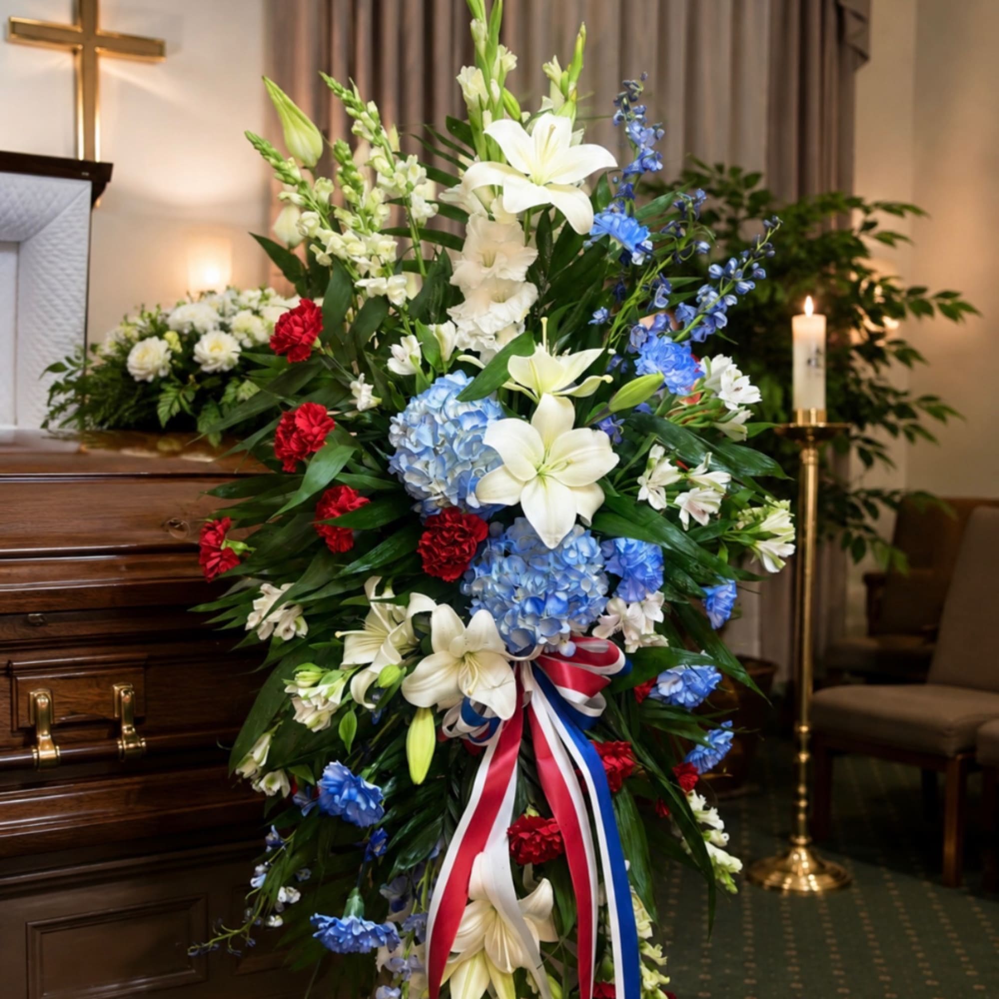 Standing funeral spray with white lilies, blue hydrangeas, and red carnations