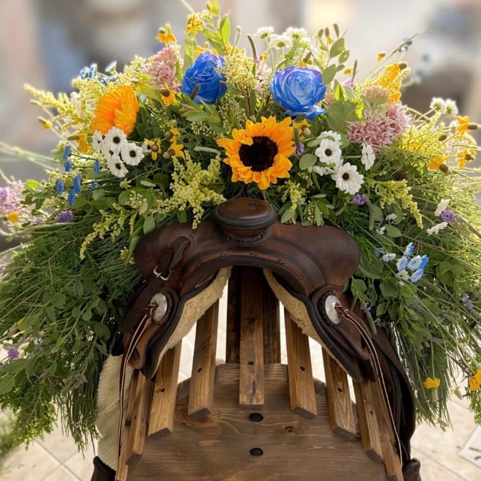 A decorative saddle draped in a cascade of bright blue roses, cheery
