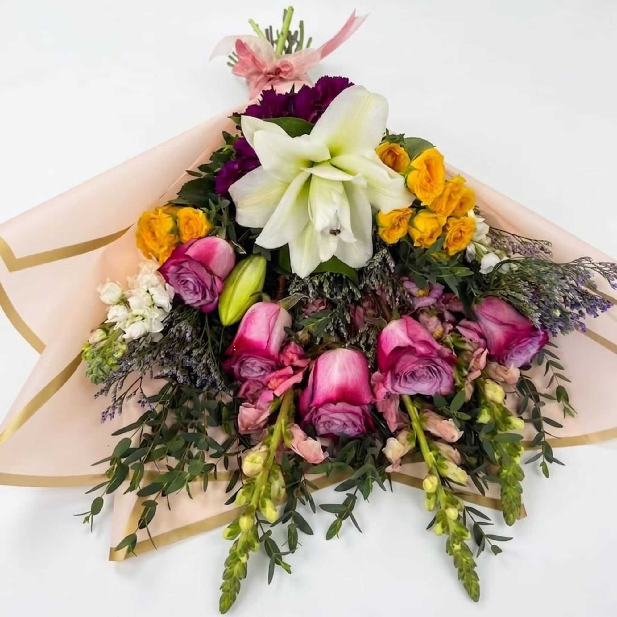 A large white lily crowns this hand-tied flower arrangement, its open trumpet