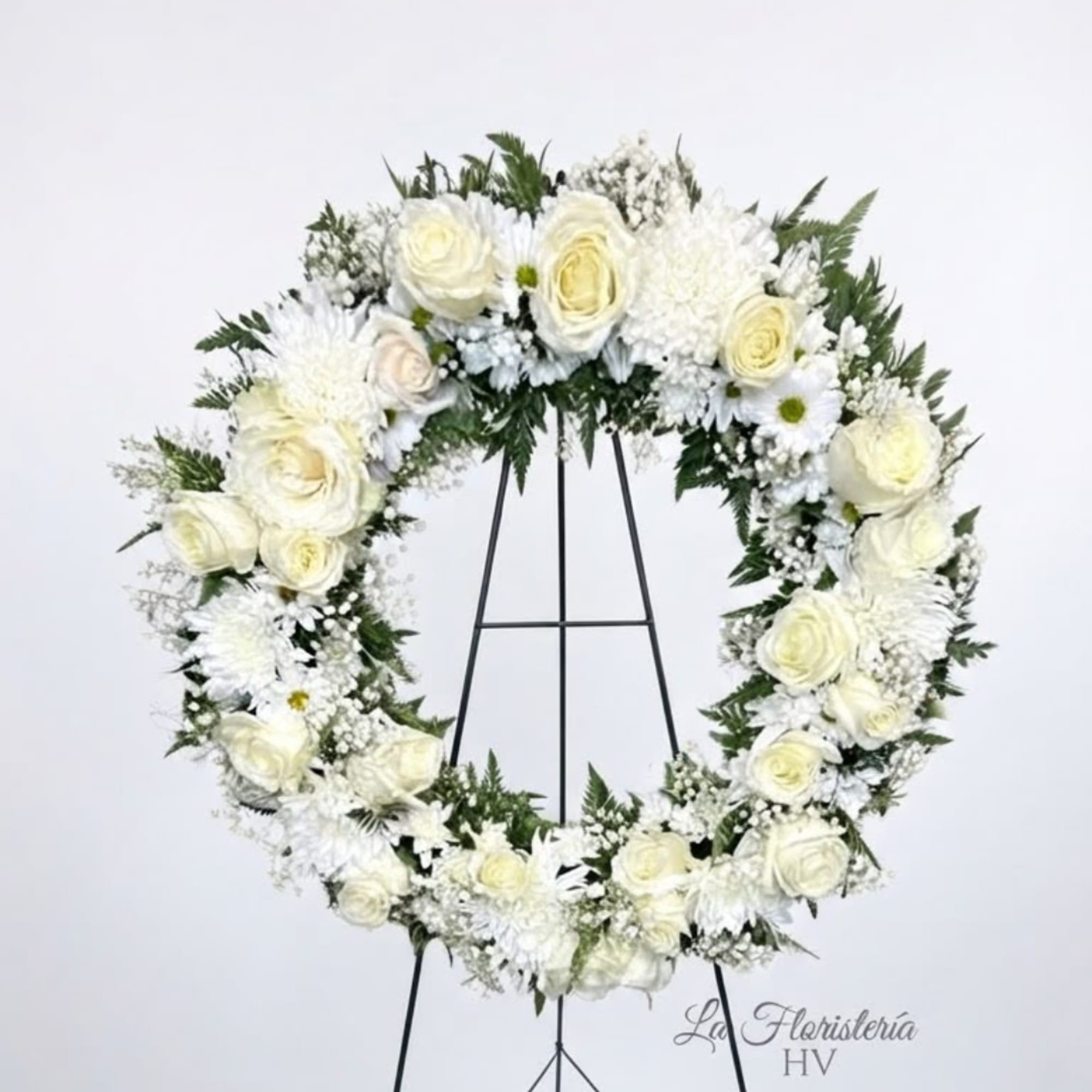 White floral wreath on a black stand
