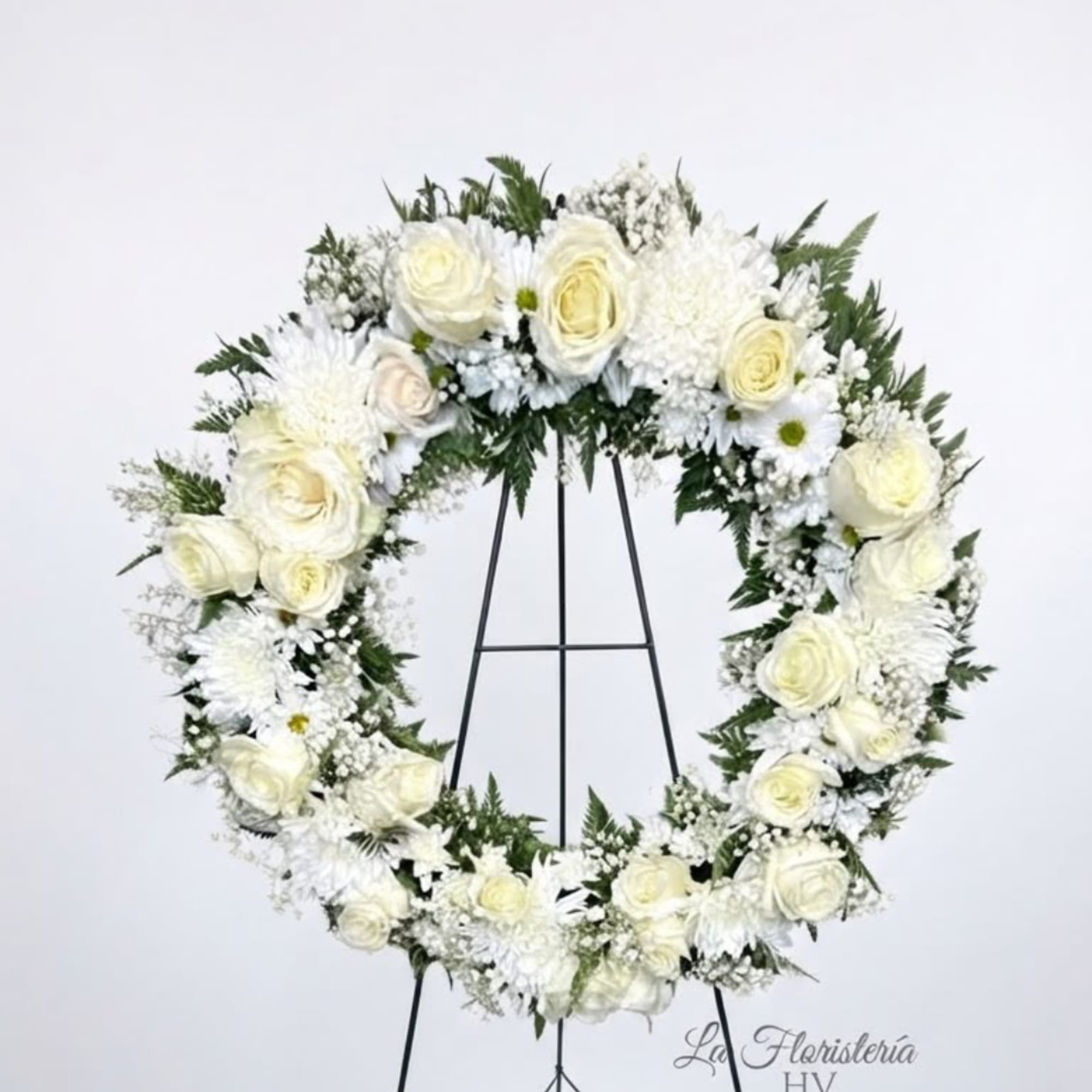 White floral wreath on a black stand