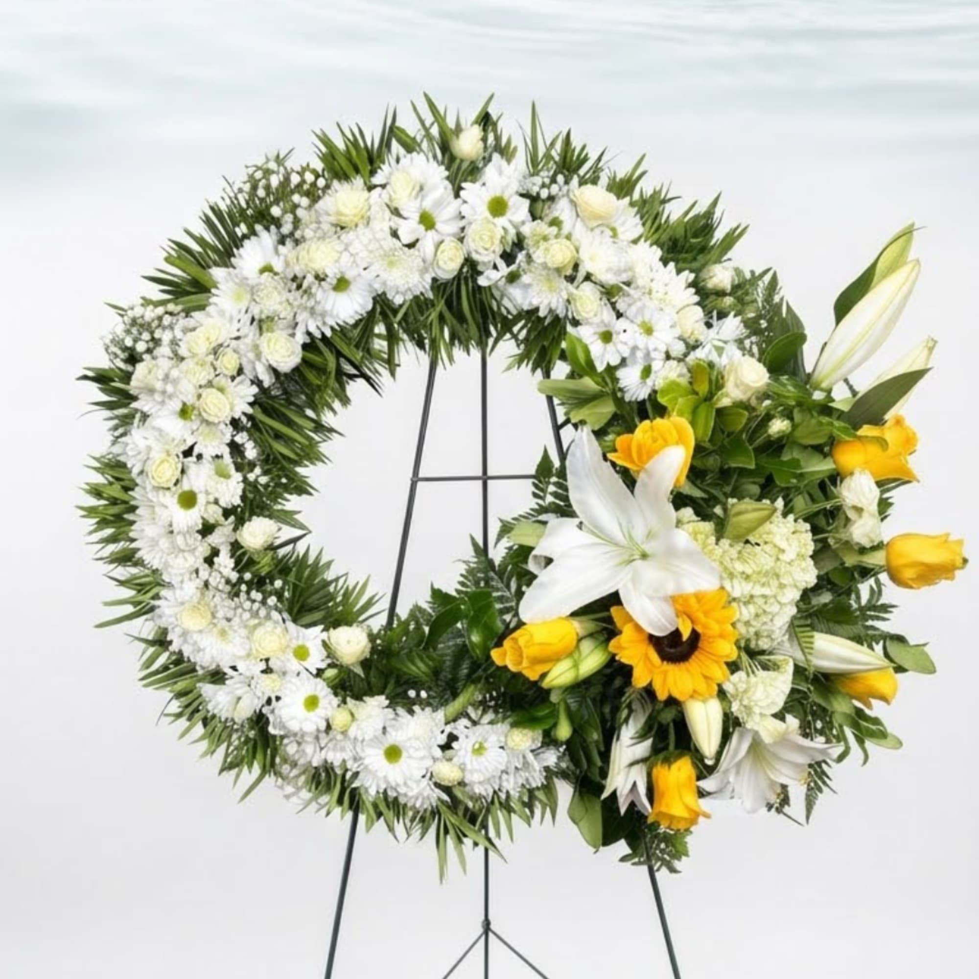 White and yellow floral wreath on a stand