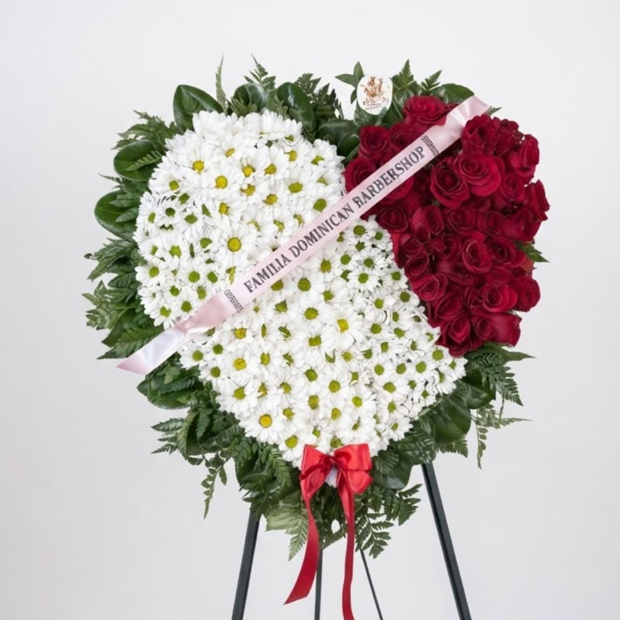 Heart-shaped floral wreath with white daisies and red roses on an easel