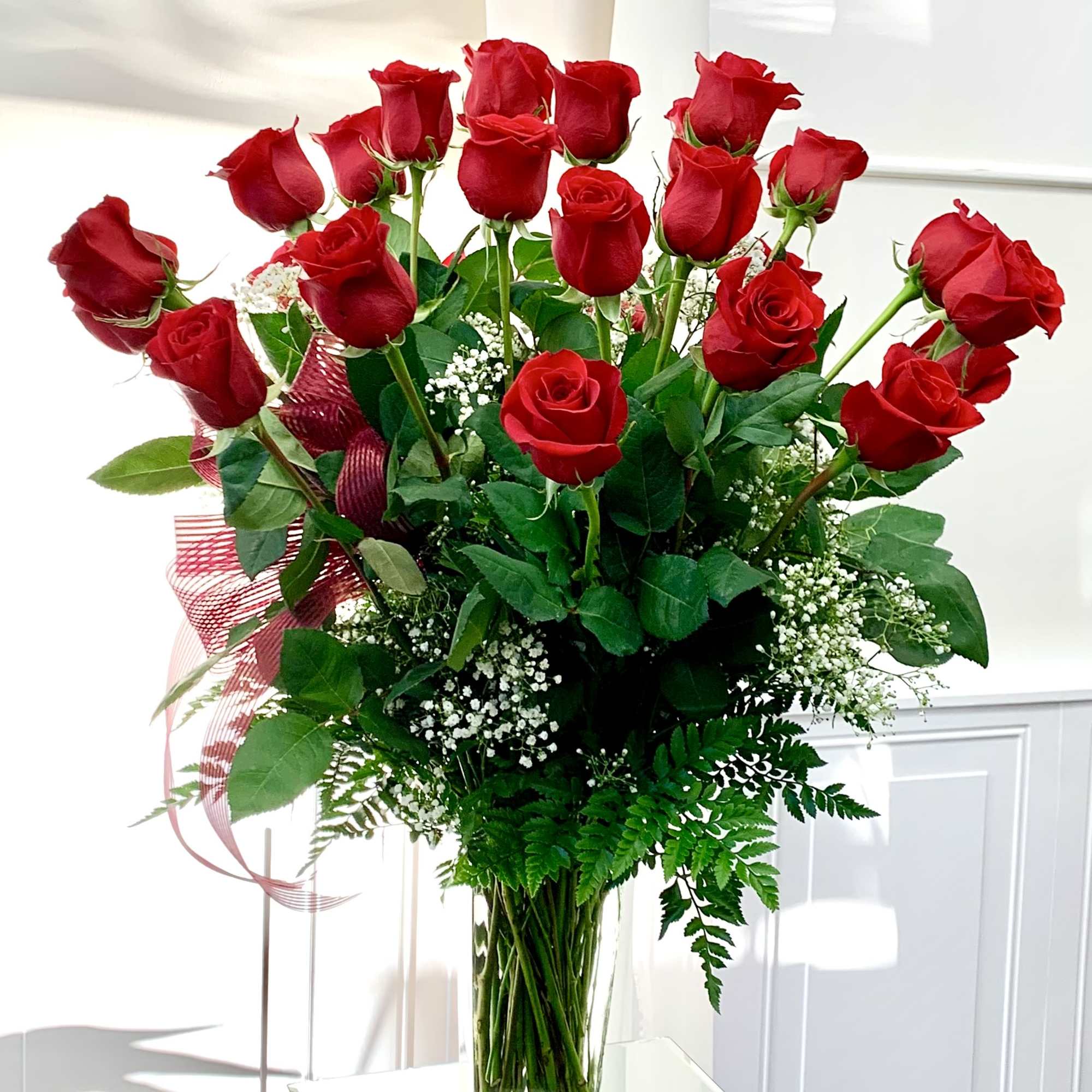 Tall bouquet of red roses in a clear glass vase