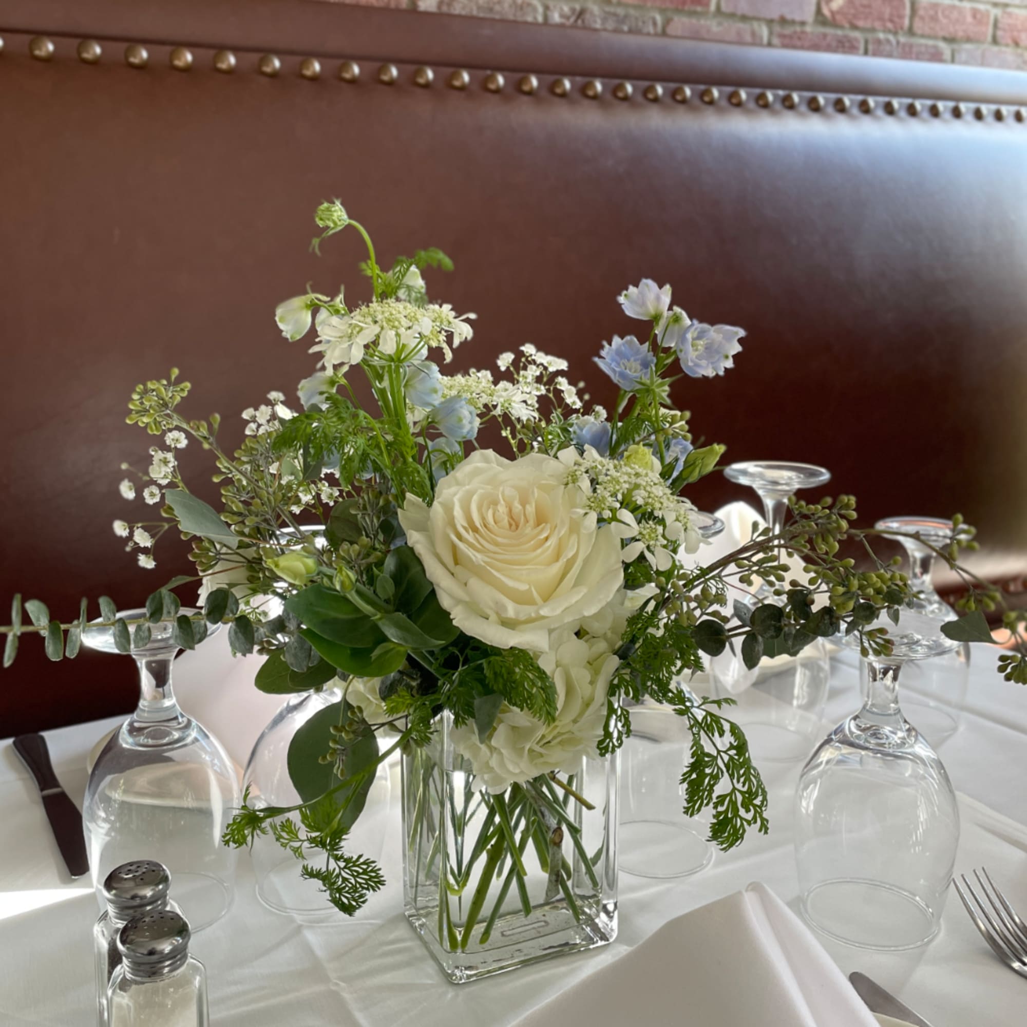 White and pale blue floral centerpiece in a clear glass vase
