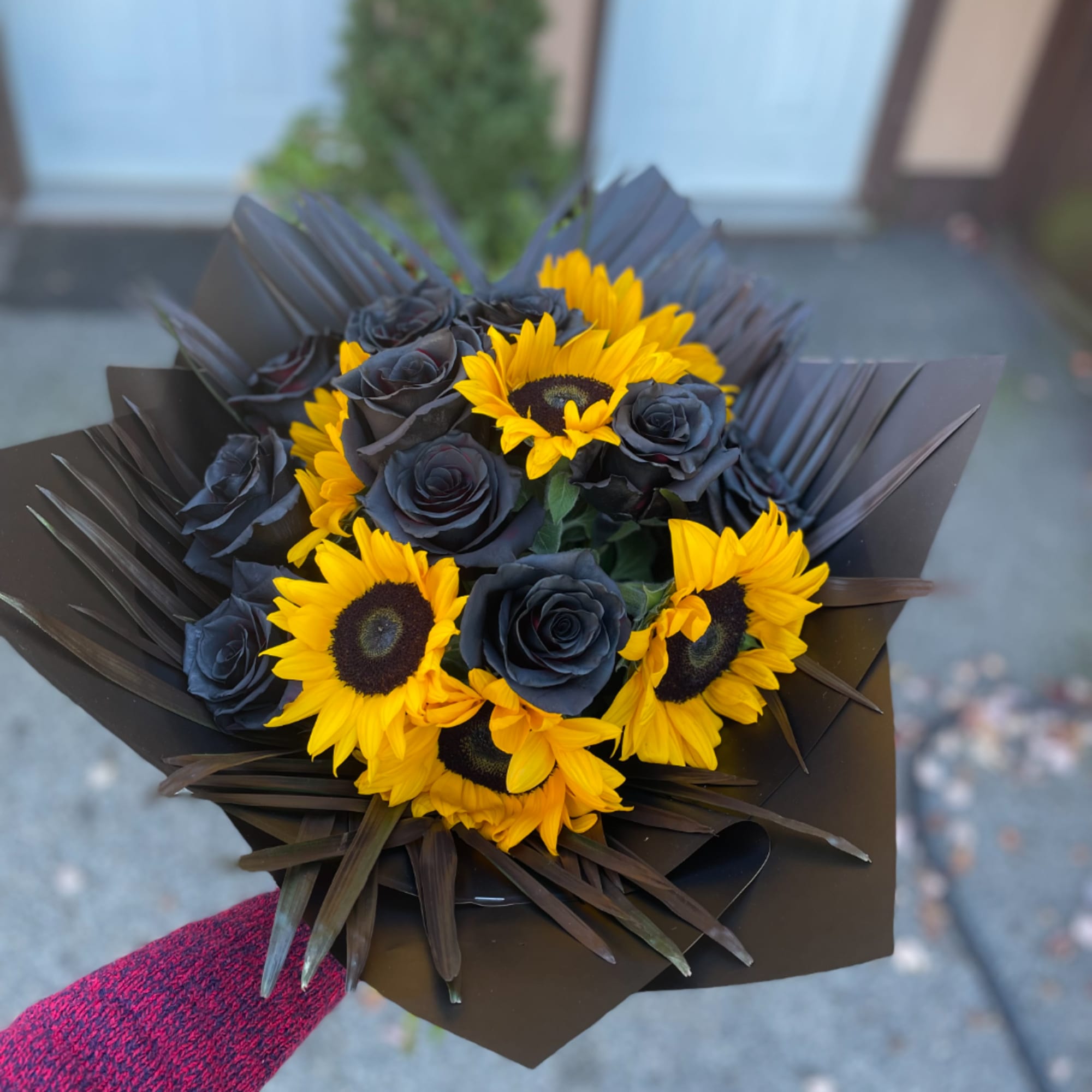 Bouquet of yellow sunflowers and dark roses wrapped in black paper
