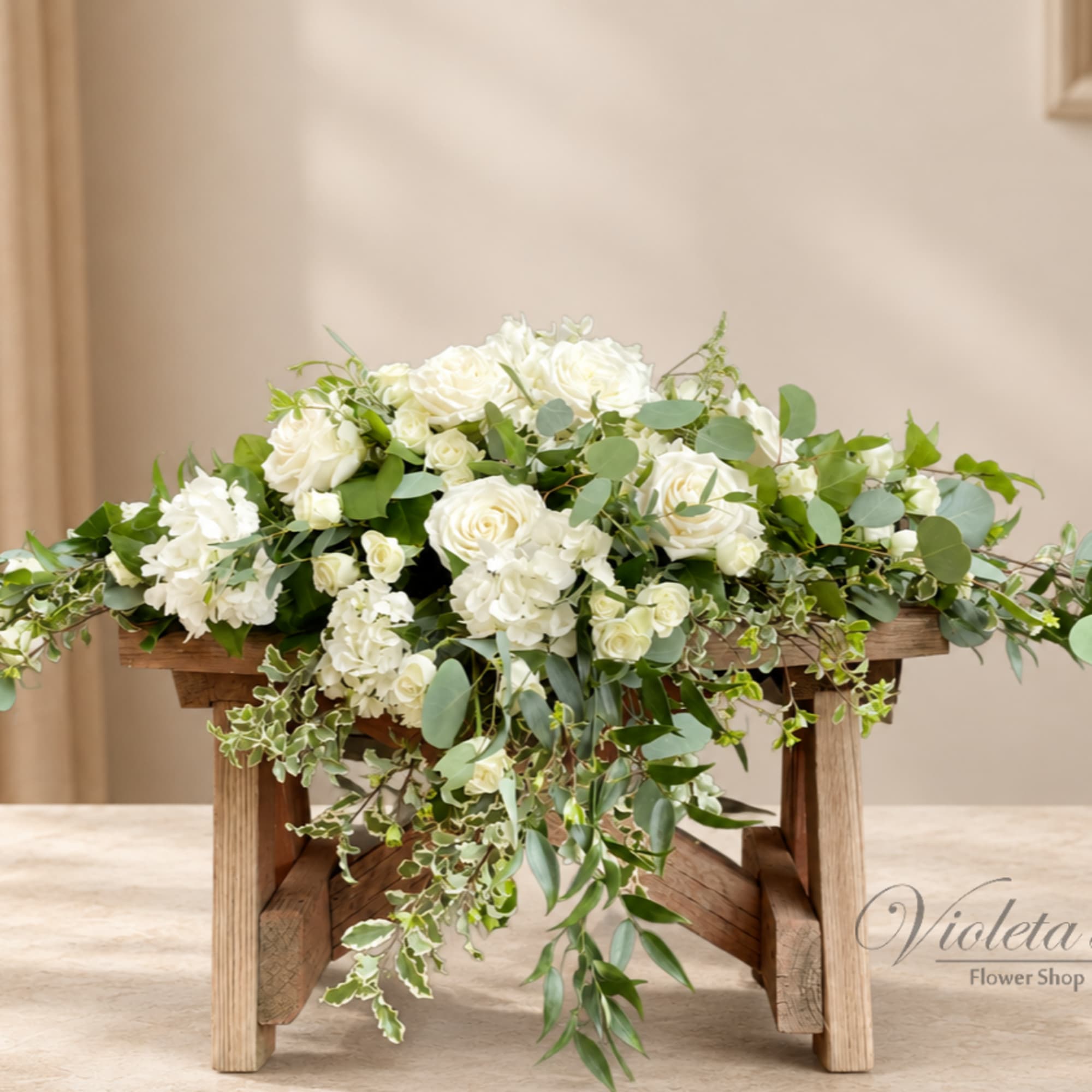 White rose arrangement with cascading greenery on a wooden stand