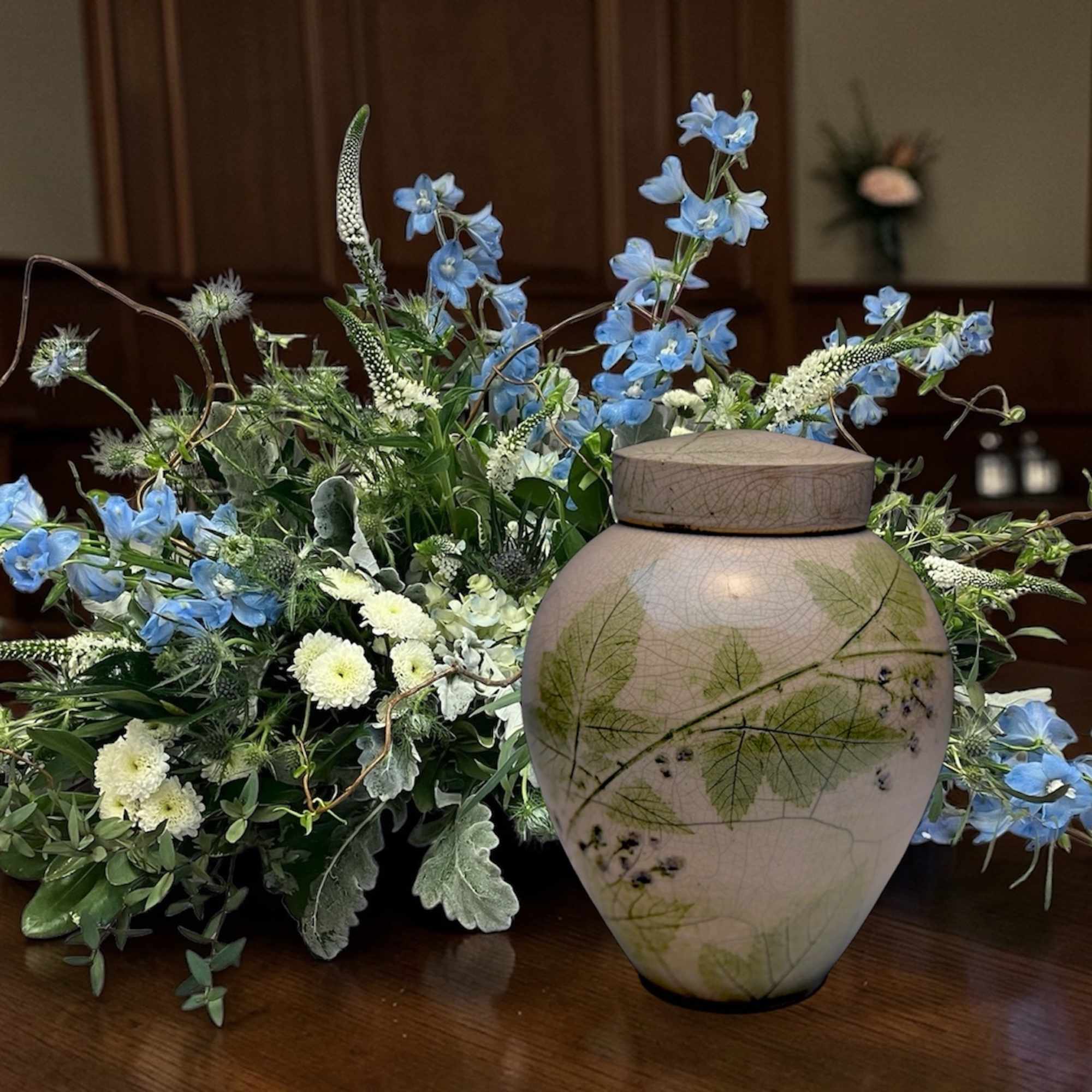 Blue and white floral arrangement beside a decorative urn on a table