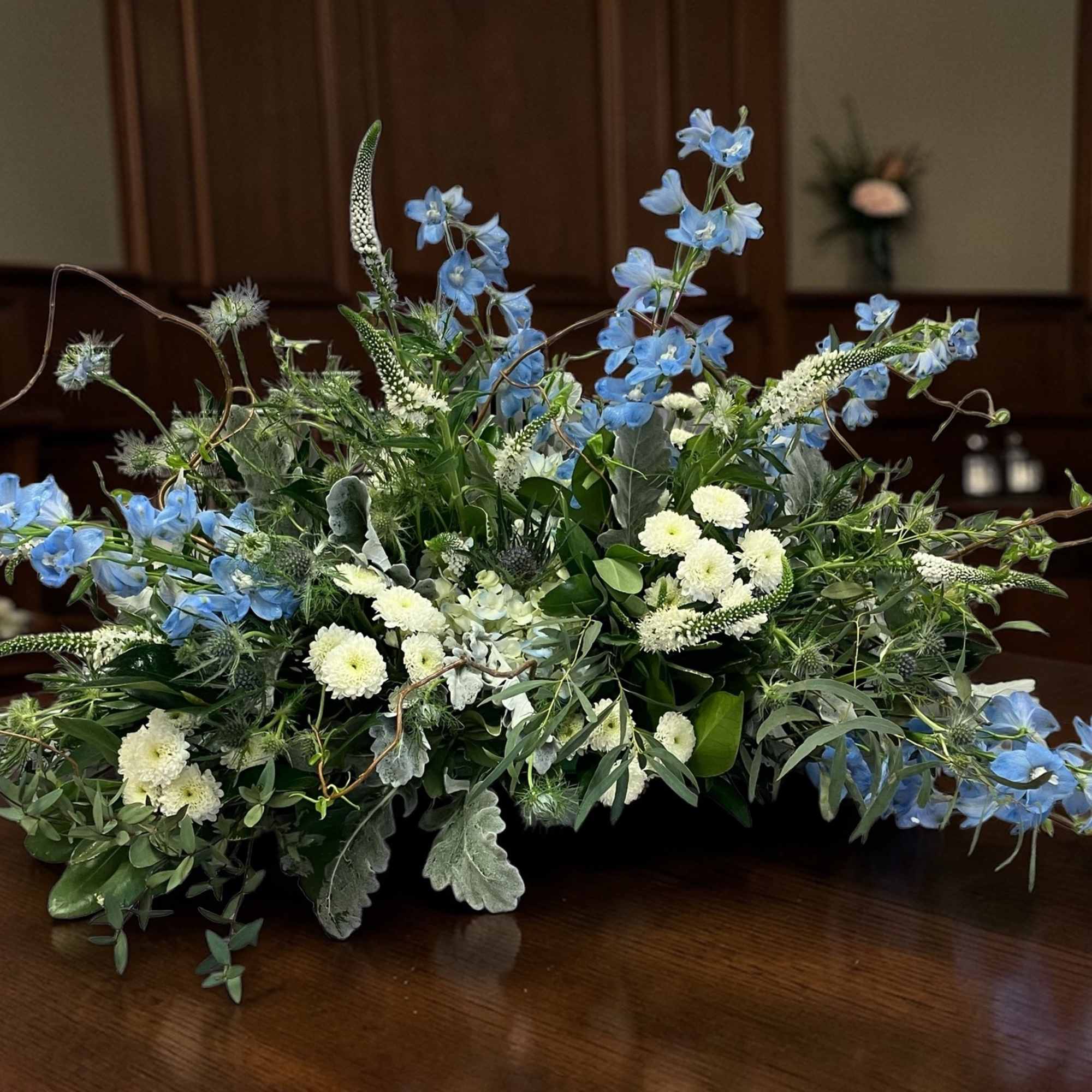Low floral arrangement with blue and white flowers on a table