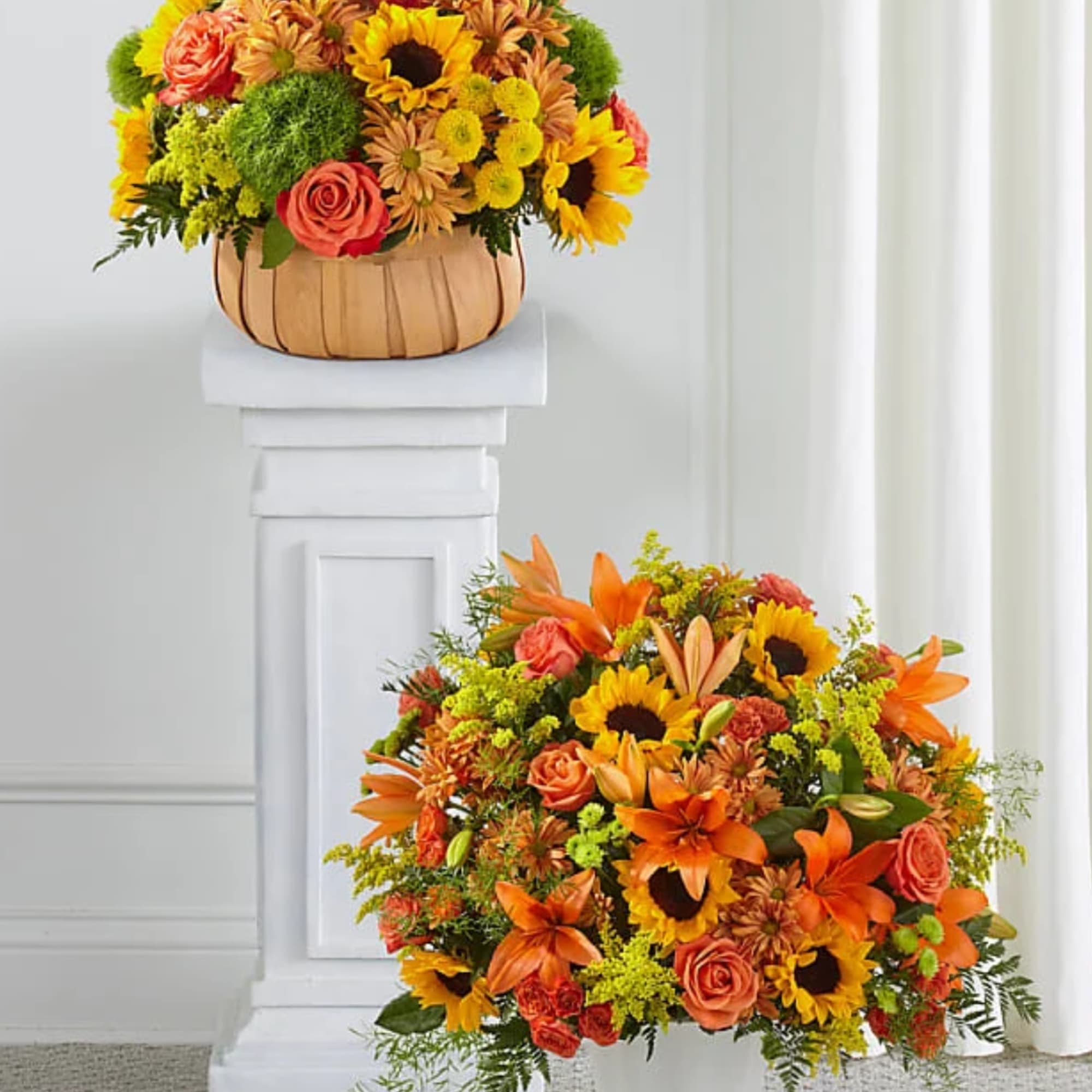 Two orange and yellow floral arrangements, one in a basket and one low centerpiece