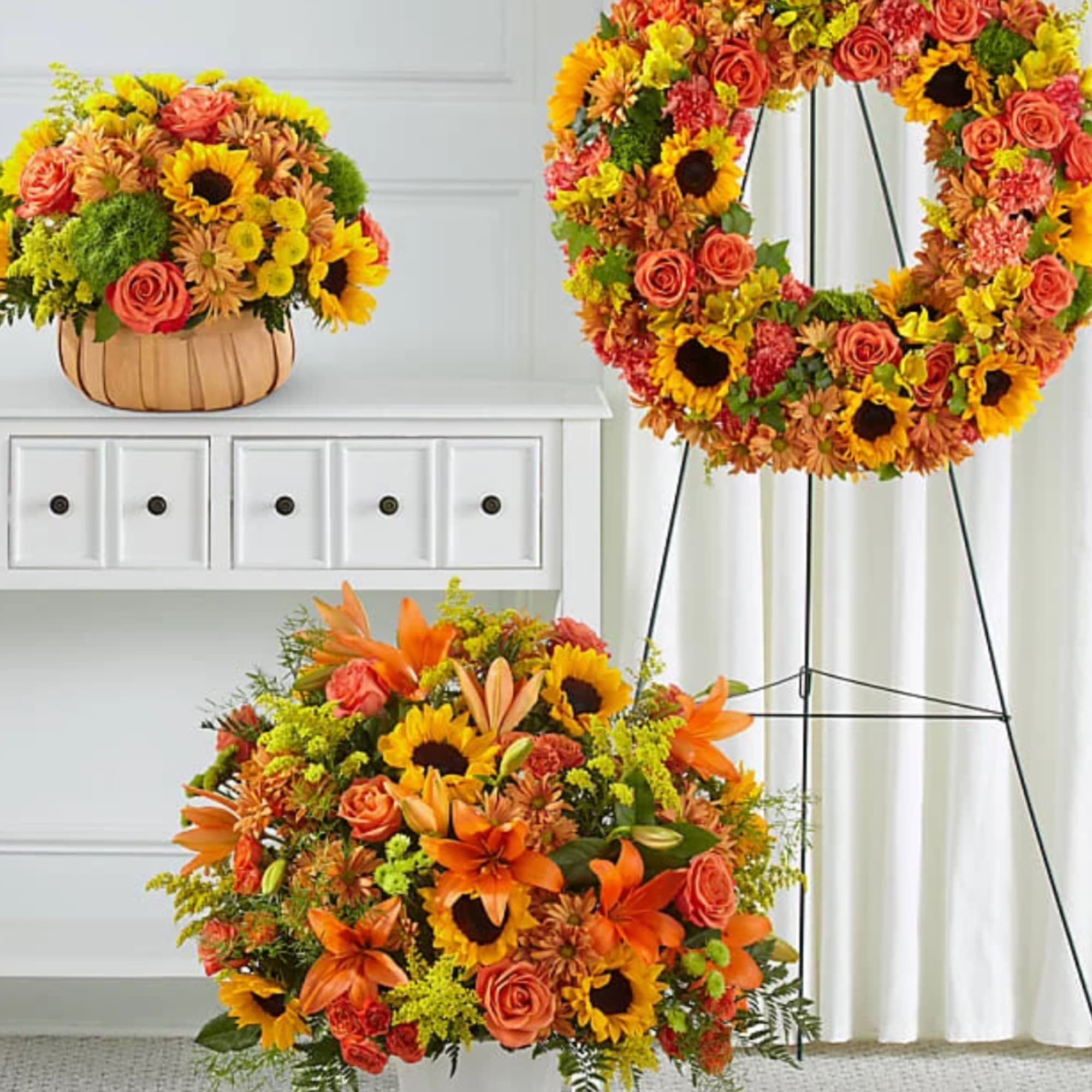 Orange and yellow floral arrangements with sunflowers and roses in a basket and wreath