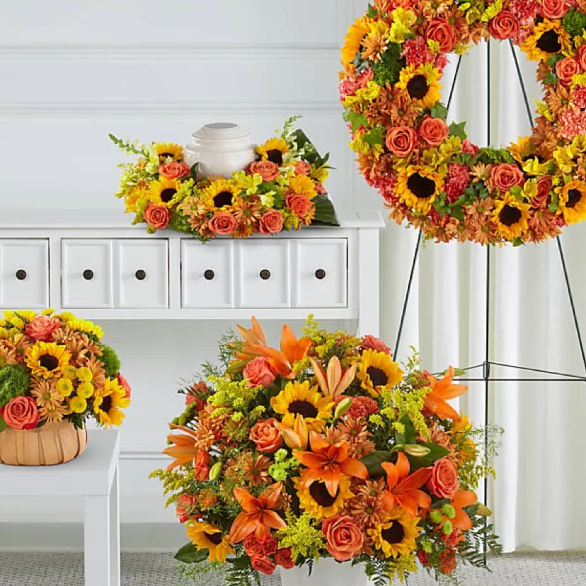 Bright mixed flower arrangements with sunflowers and orange roses in white and basket containers