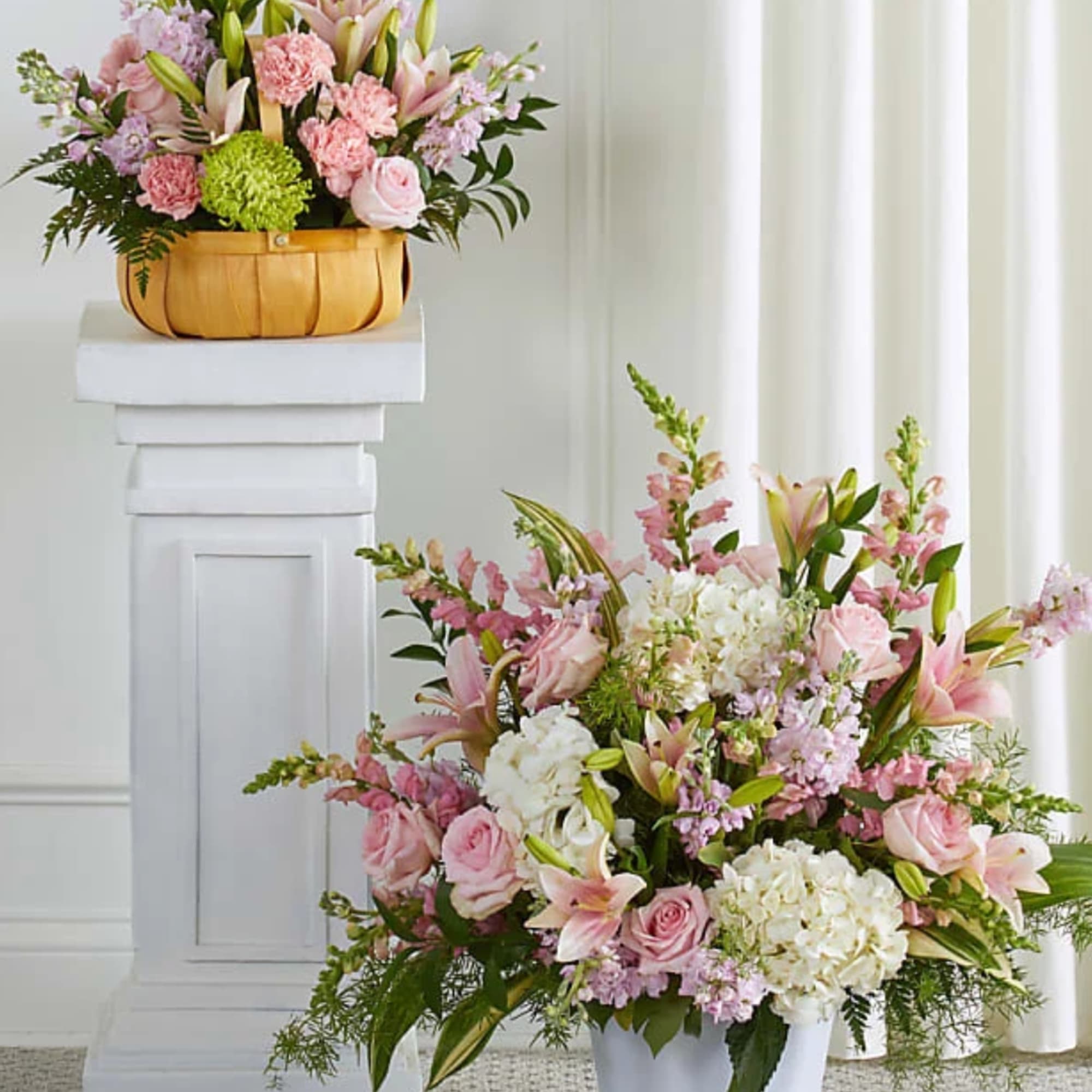 Pink and white floral arrangements in a basket and white vase