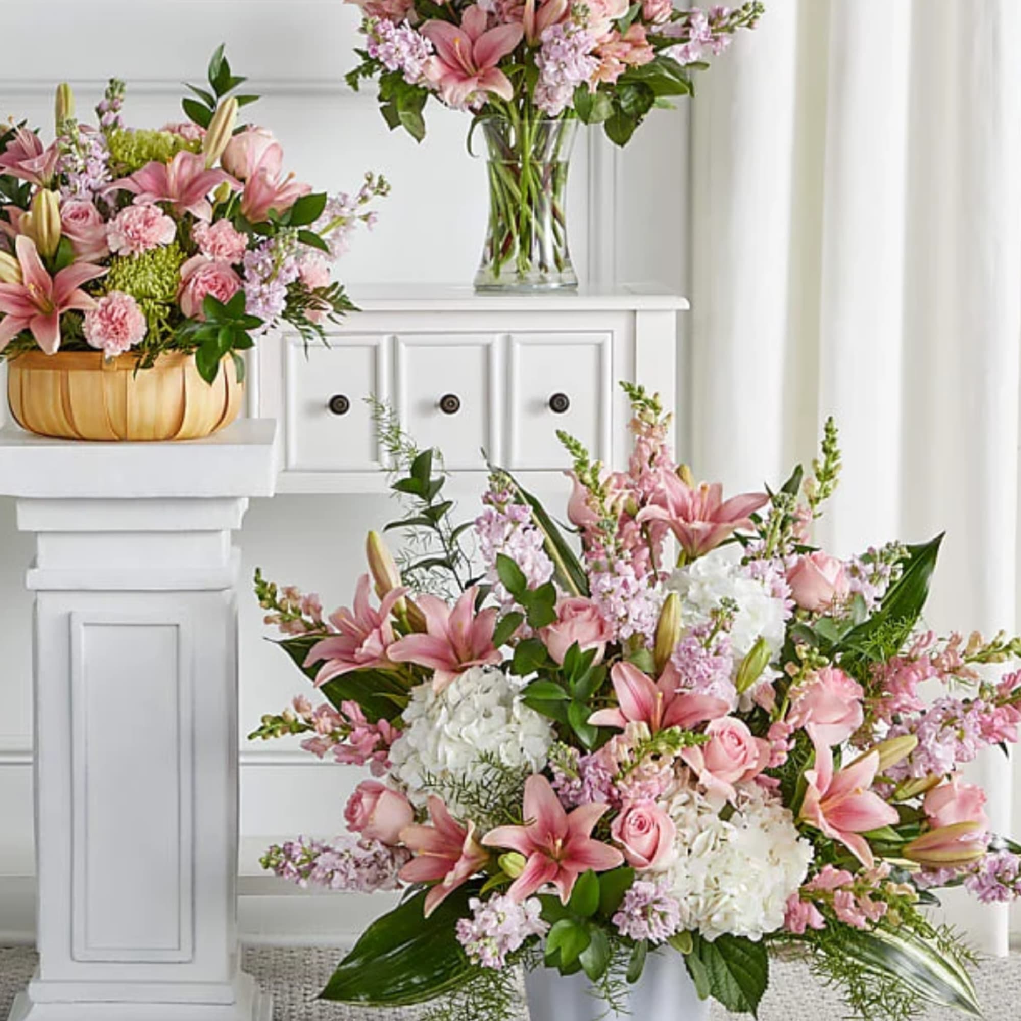 Pink lilies and roses arranged with white hydrangeas in a vase