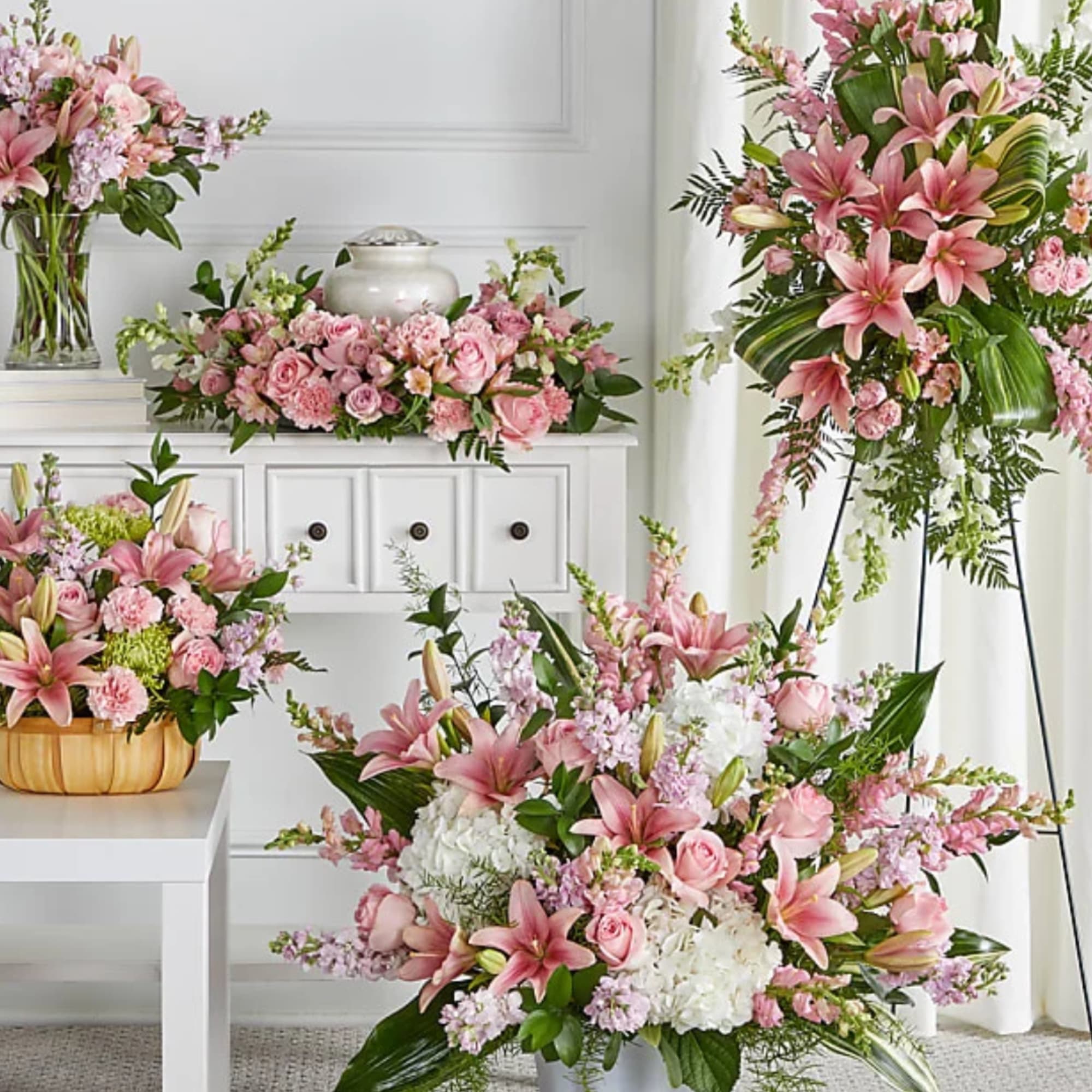 Pink and white floral arrangements with lilies and roses in vases and baskets
